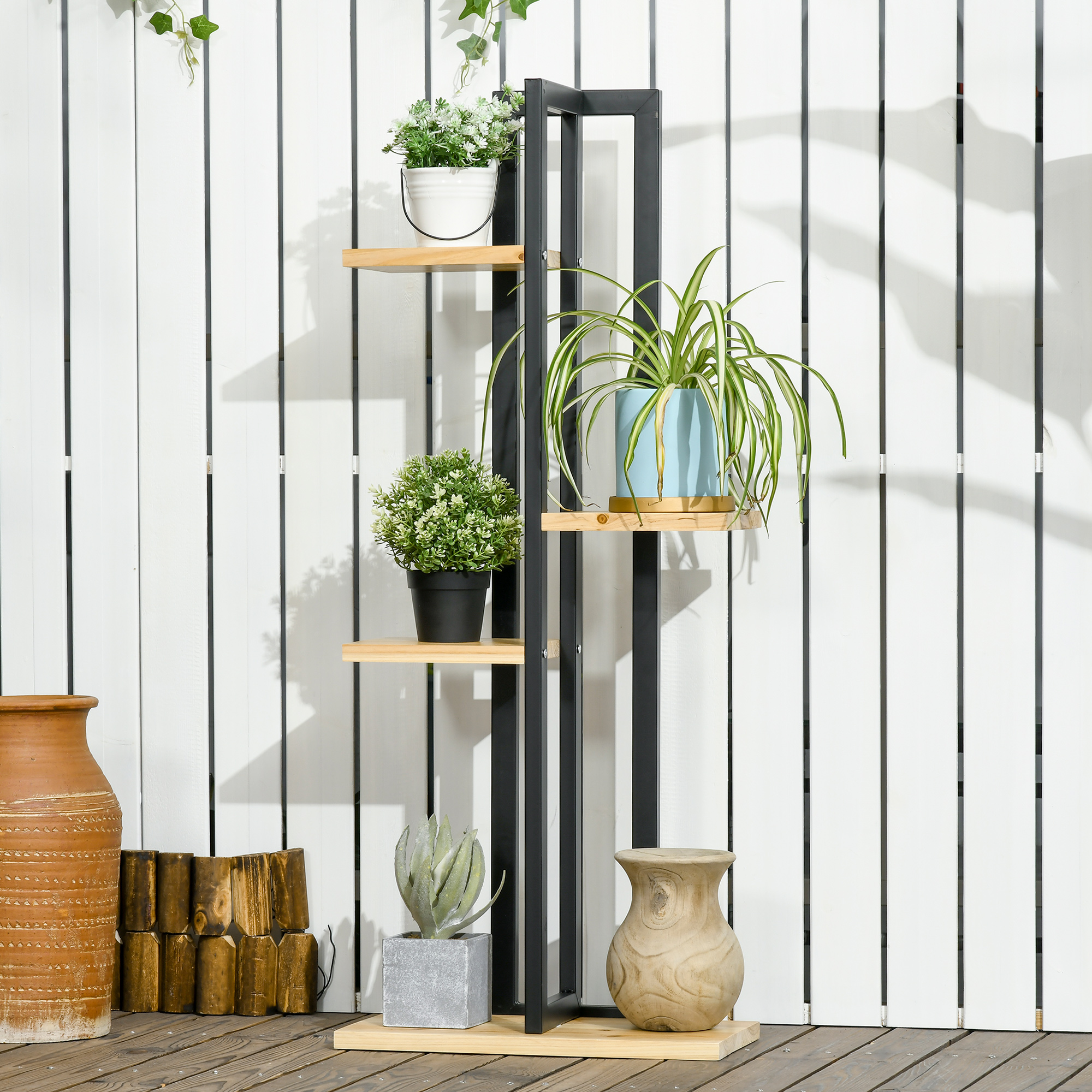Scaffale nero con ripiani in legno e piante davanti a una parete di legno bianca.