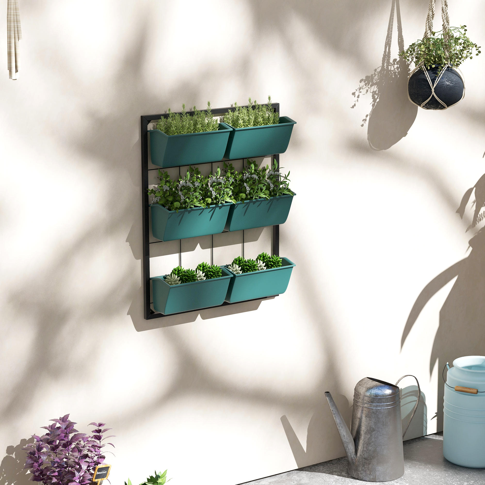 Giardini verticali con piante verdi su un muro, accanto a un annaffiatoio.