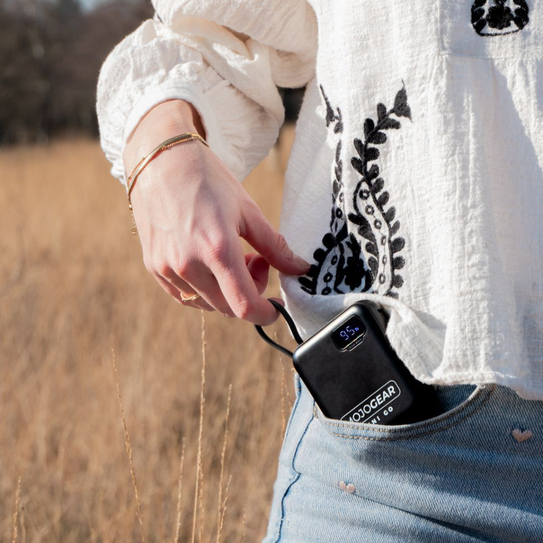 A woman pulls a black power bank showing 95% charge from her jeans pocket.