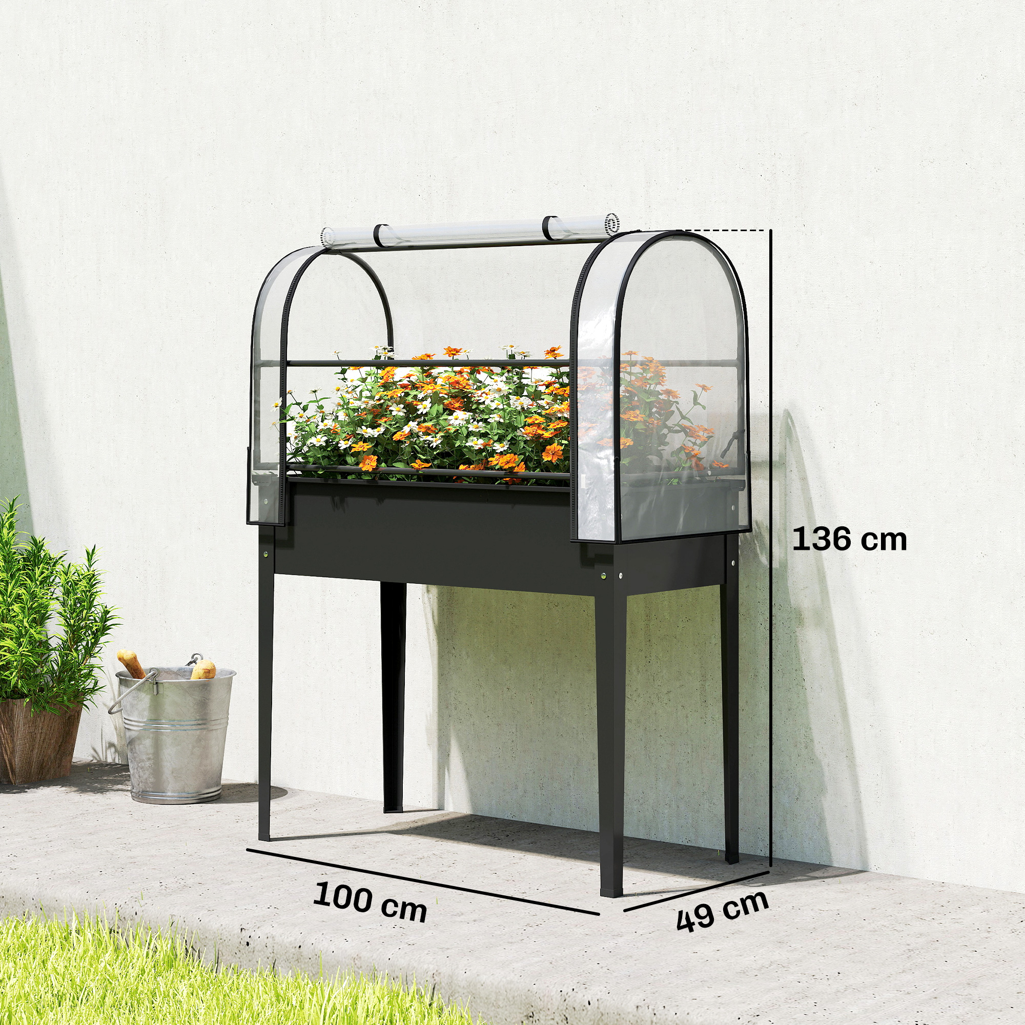 Una fioriera rialzata nera con fiori e copertura trasparente si trova su un pavimento in cemento.