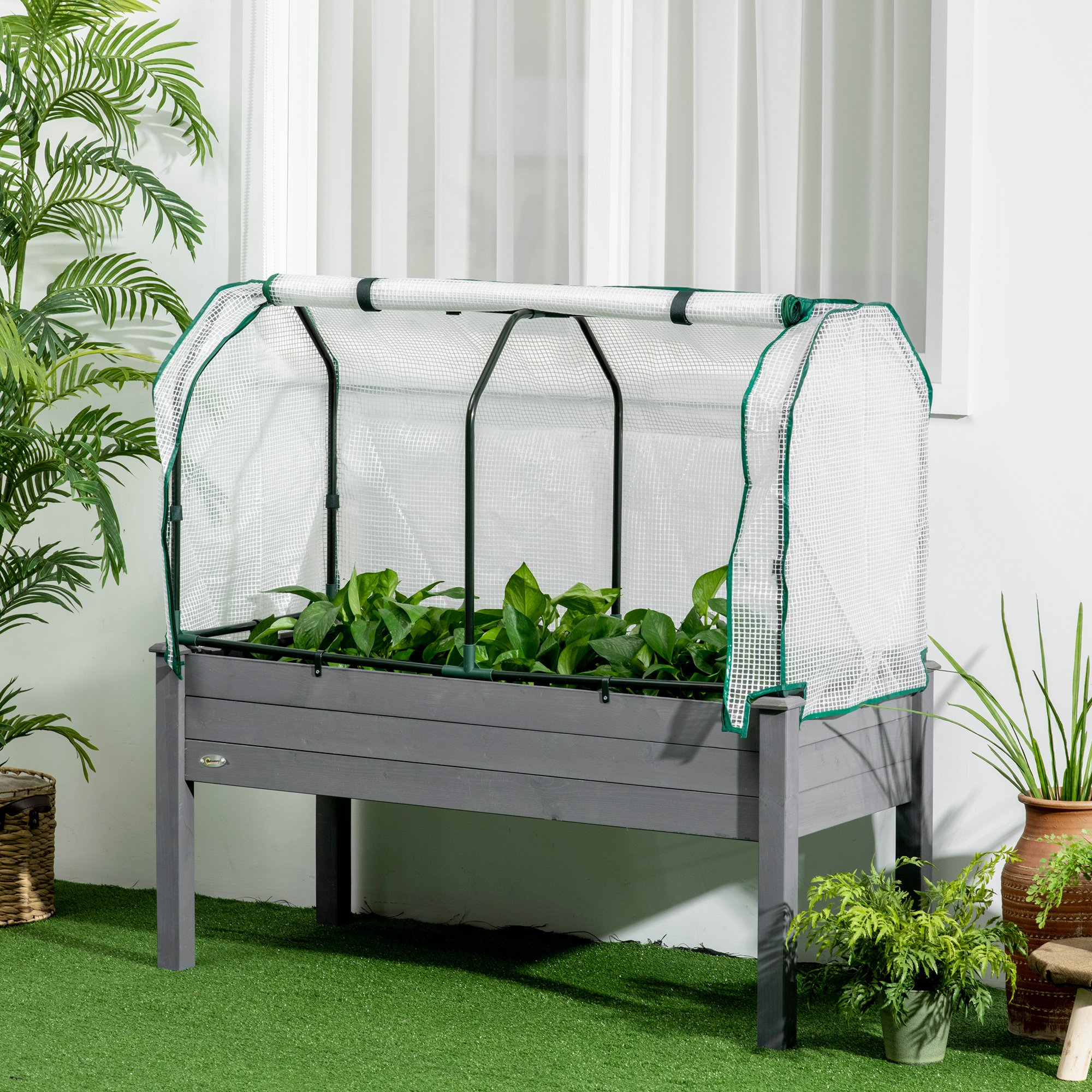 Un letto rialzato con copertura a serra e piante verdi all'interno.