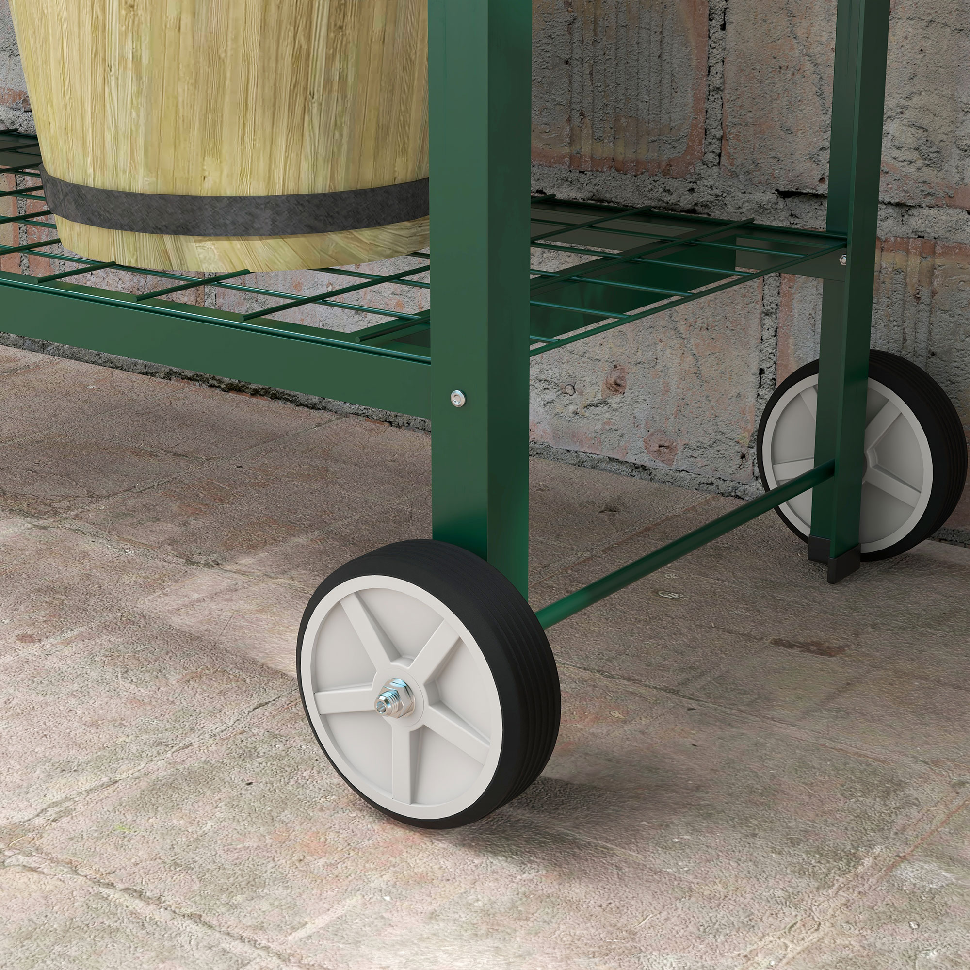 Carrello verde in metallo con botte di legno, due ruote e muro di mattoni.