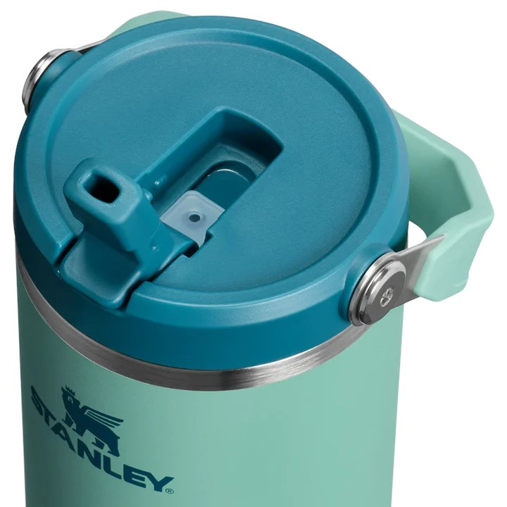 Turkuaz kapaklı ve saplı yeşil su şişesi. Stanley logosu görünüyor.