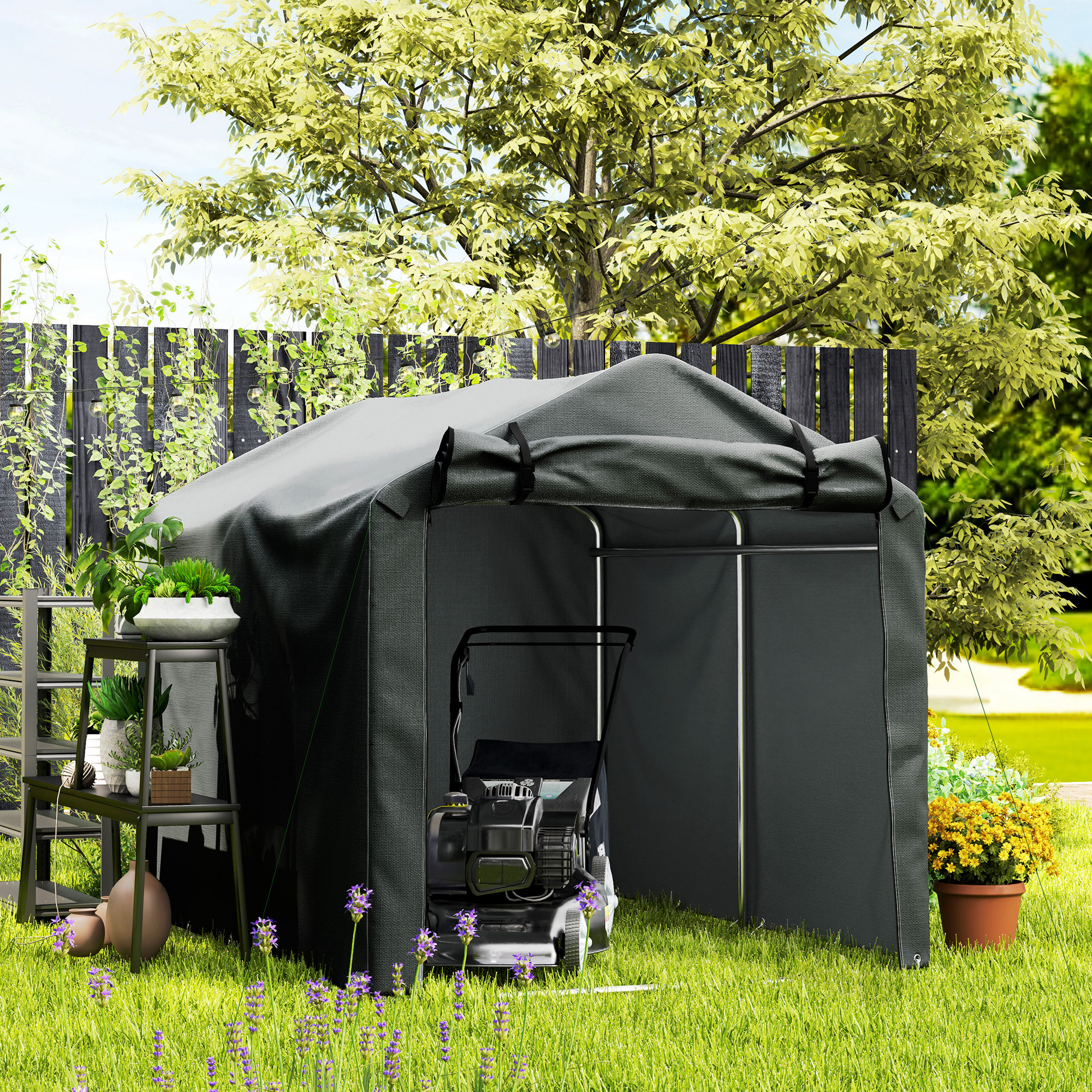 Una tenda grigio scuro per attrezzature da giardino si trova sull'erba con un tosaerba all'interno.