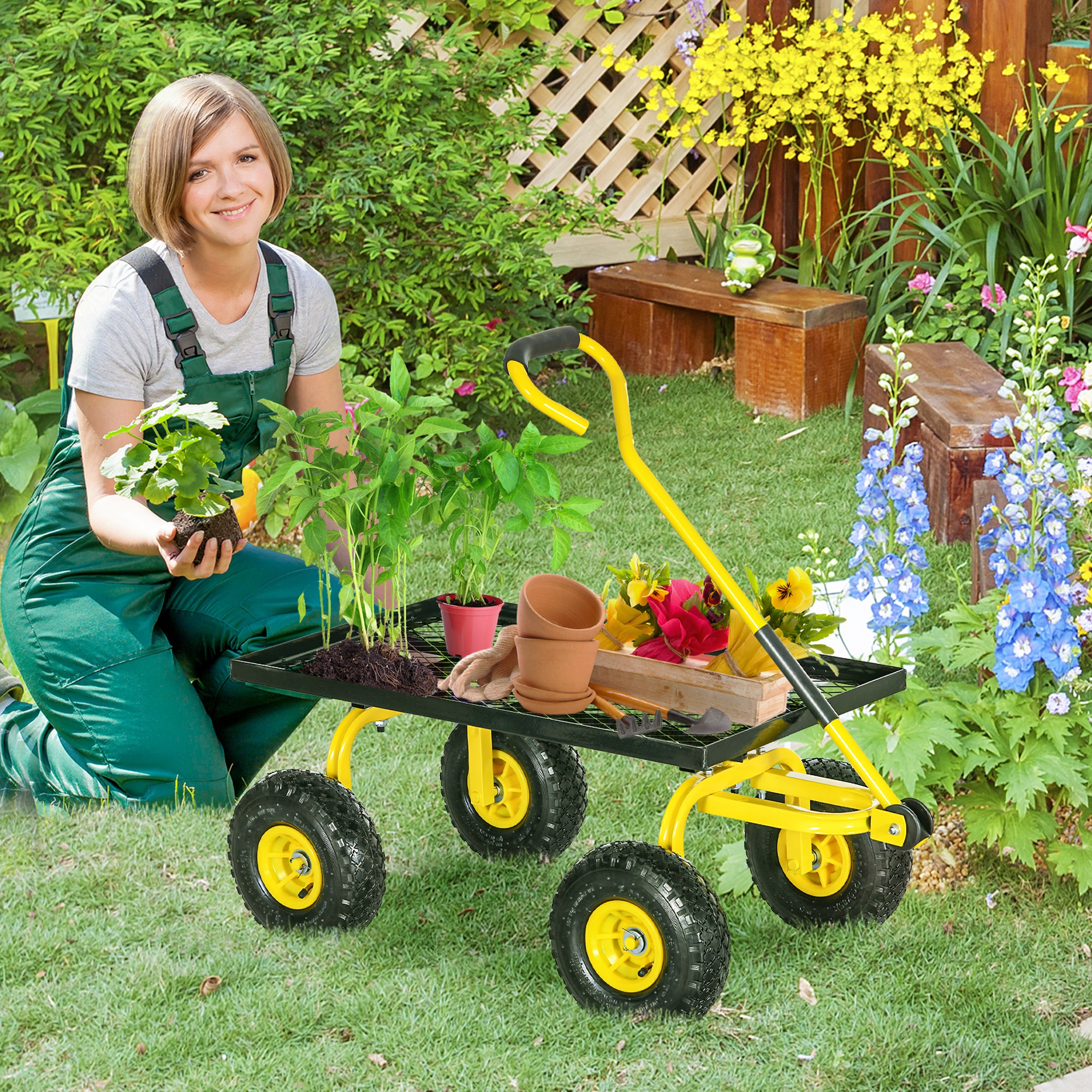 Una donna in salopette pianta una piantina vicino a un carrello da giardino giallo con attrezzi.