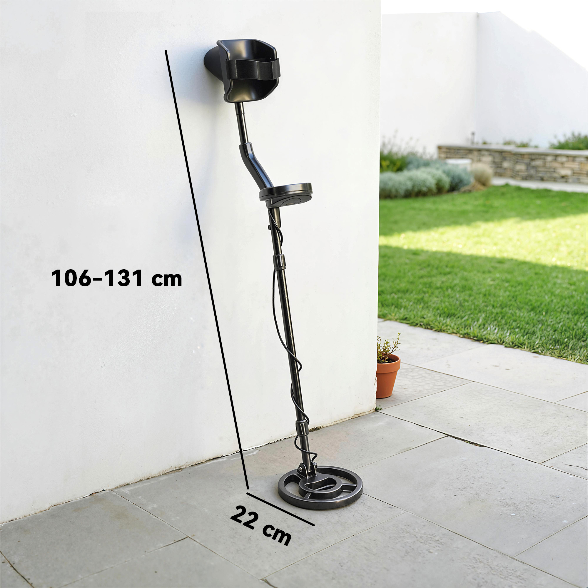 Un metal detector nero appoggiato a un muro bianco. Dimensioni: 106-131 cm altezza, 22 cm bobina.
