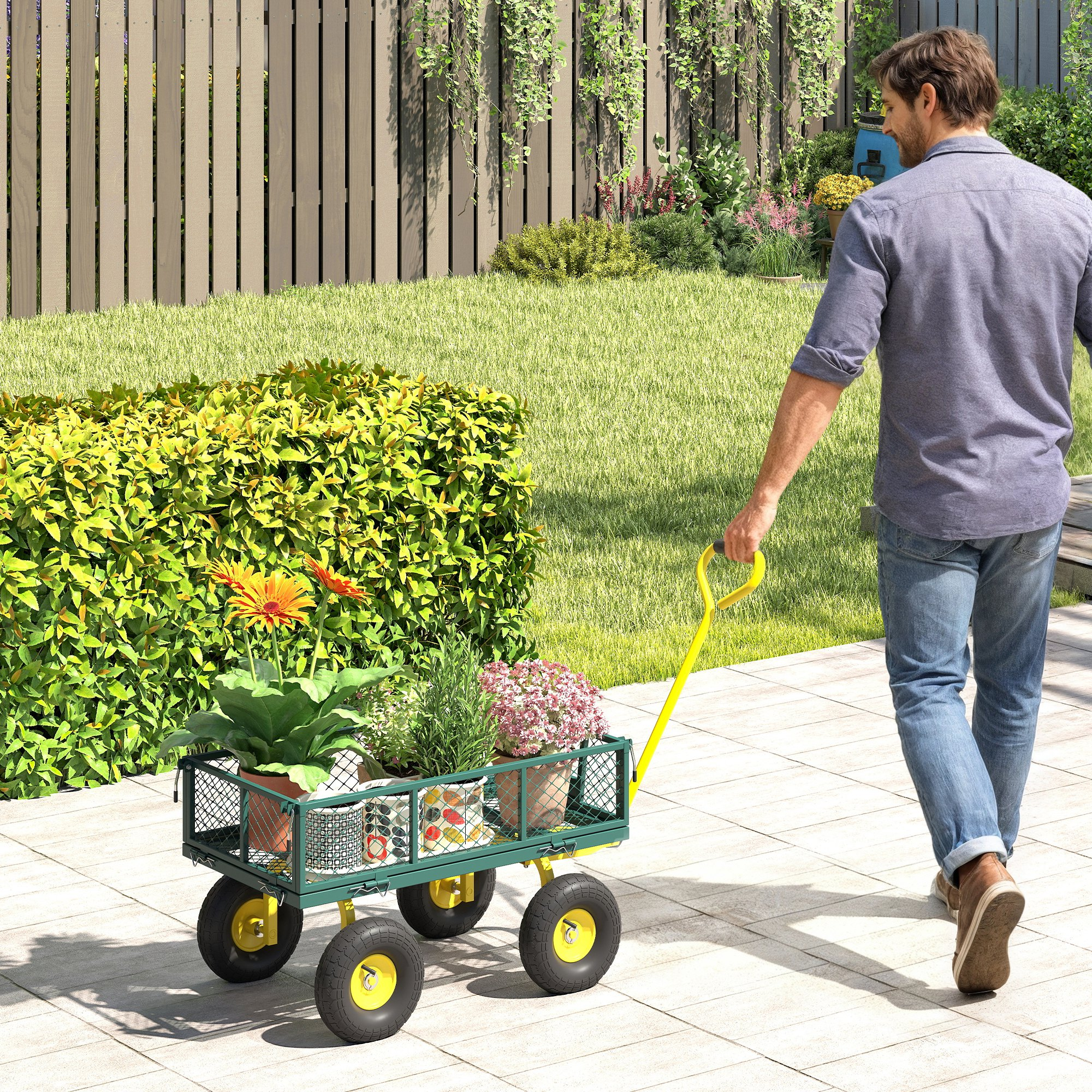 Un uomo spinge un carrello da giardino verde pieno di piante su un sentiero lastricato.
