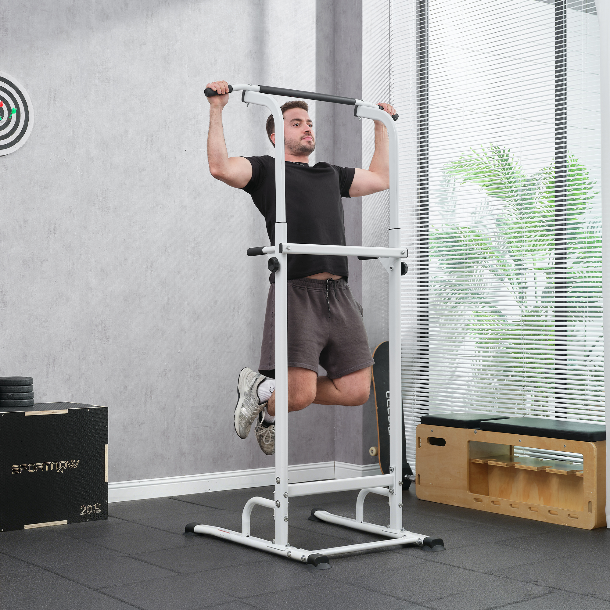 Un uomo fa trazioni su un pull-up bar bianco in una palestra con un bersaglio per freccette.
