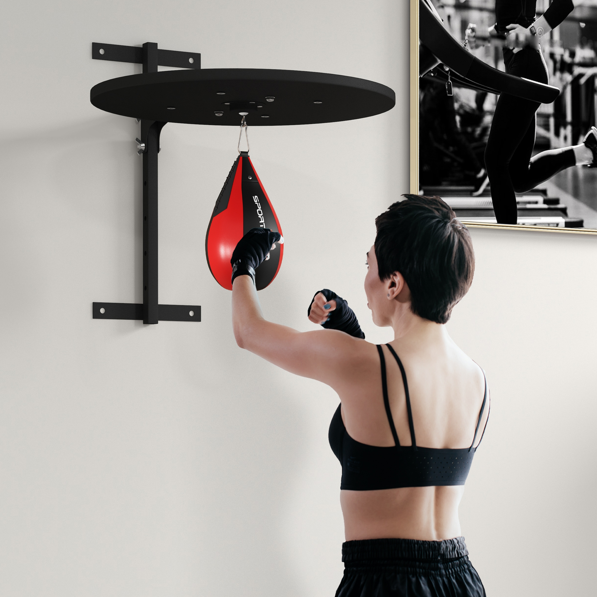 Una donna con i capelli corti colpisce un sacco da boxe rosso e nero montato sul muro.