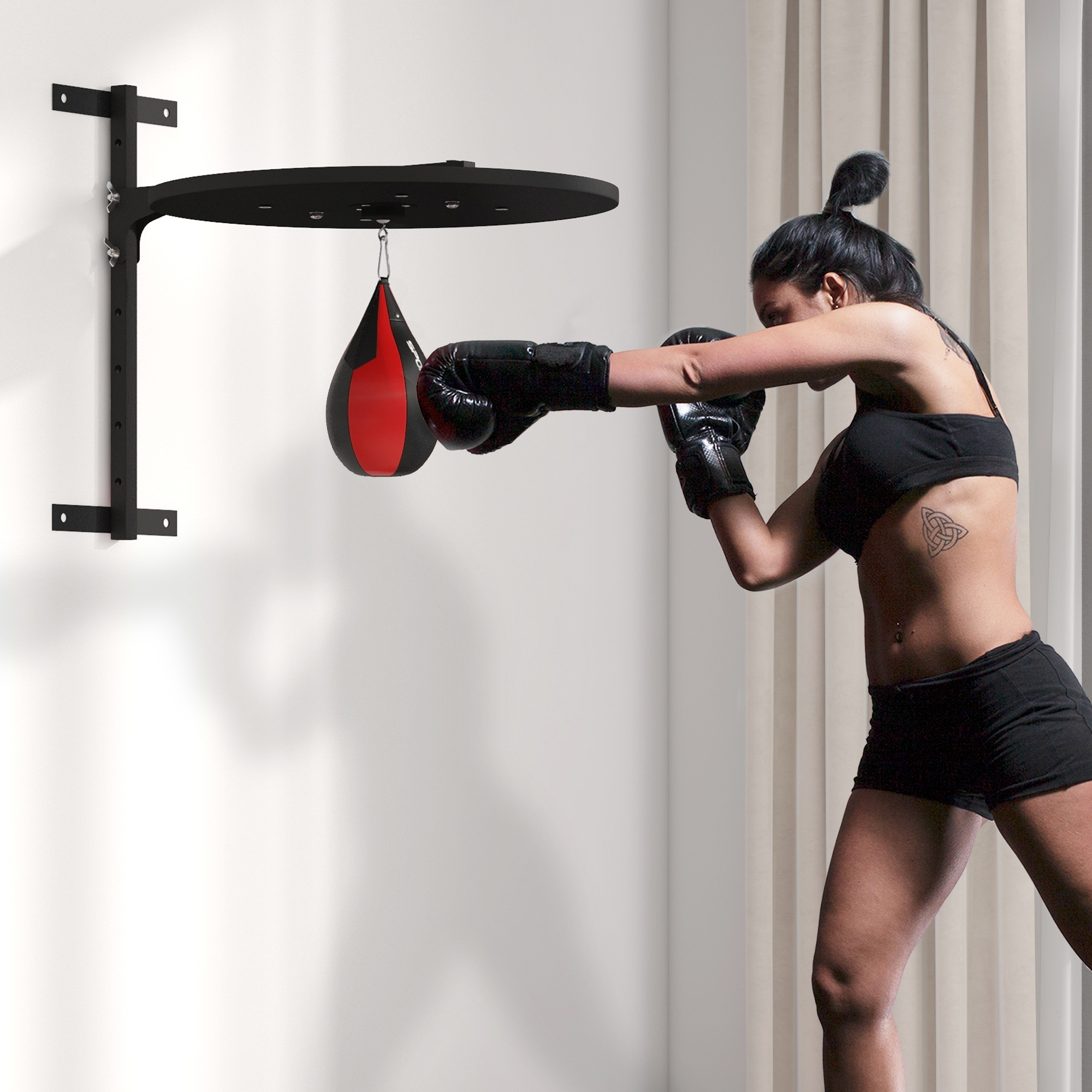 Donna che colpisce un sacco da boxe rosso e nero appeso a una staffa a muro.