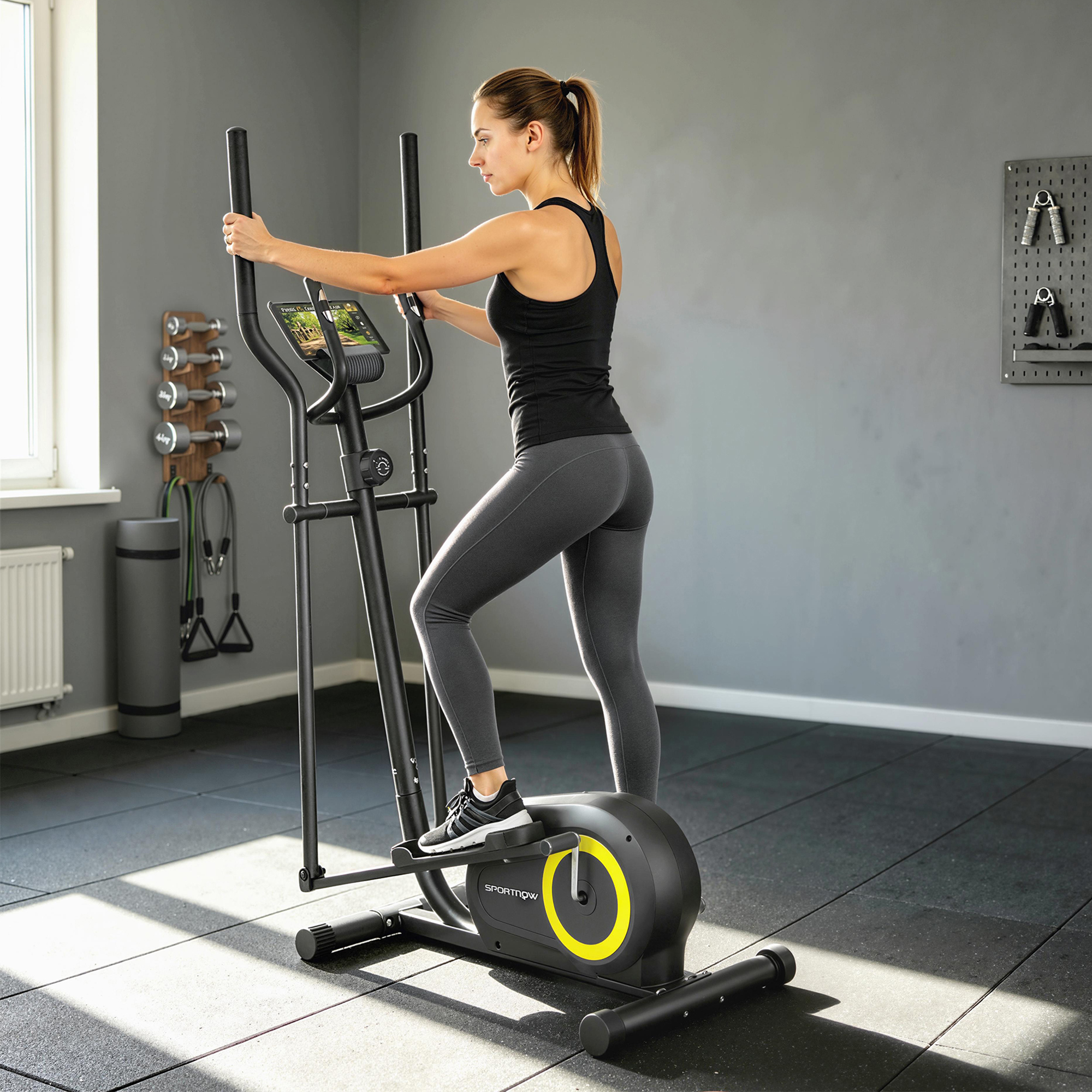 Una donna si allena su una macchina ellittica nera con accenti gialli in una palestra.
