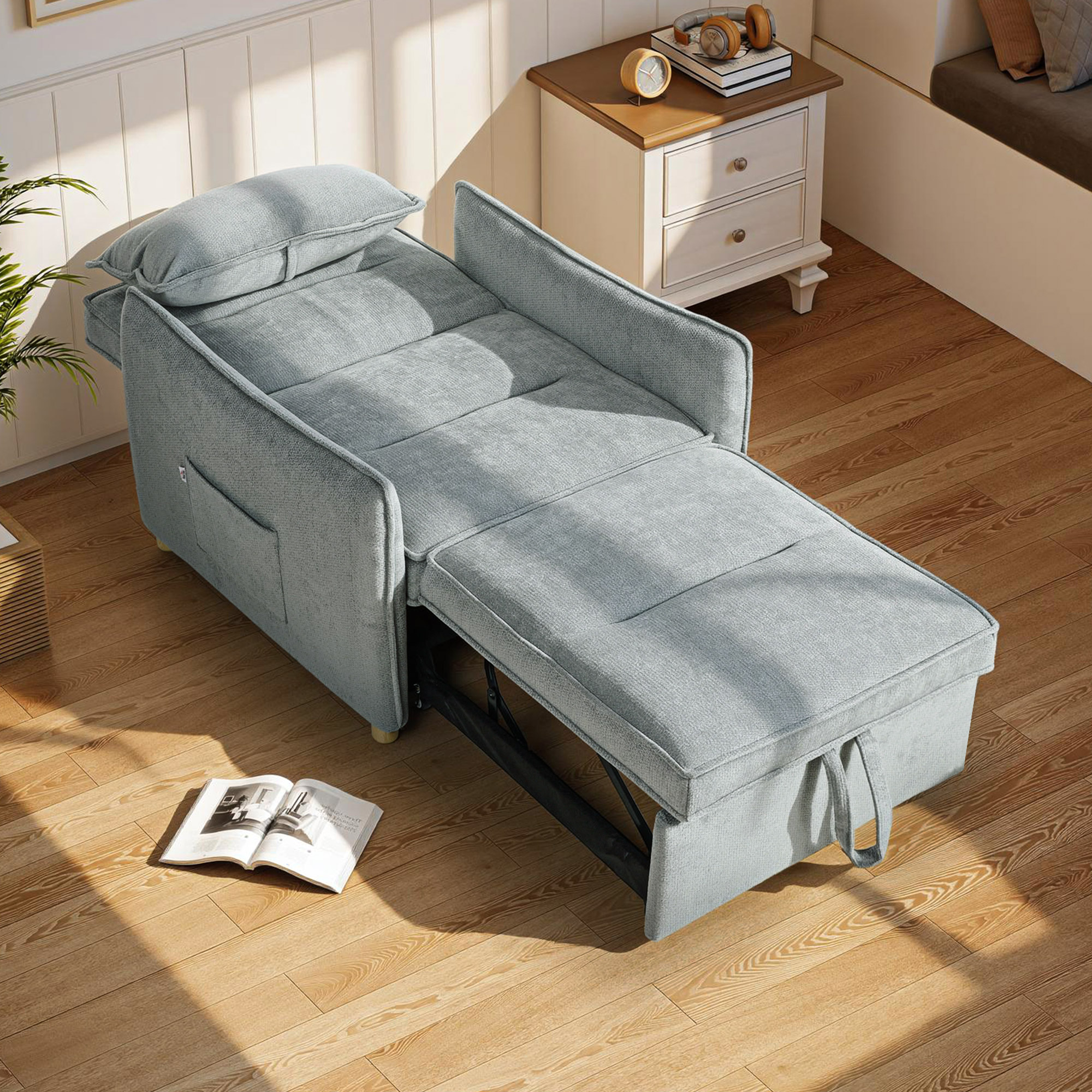 Un divano letto grigio chiaro con poggiapiedi esteso su pavimento in legno.
