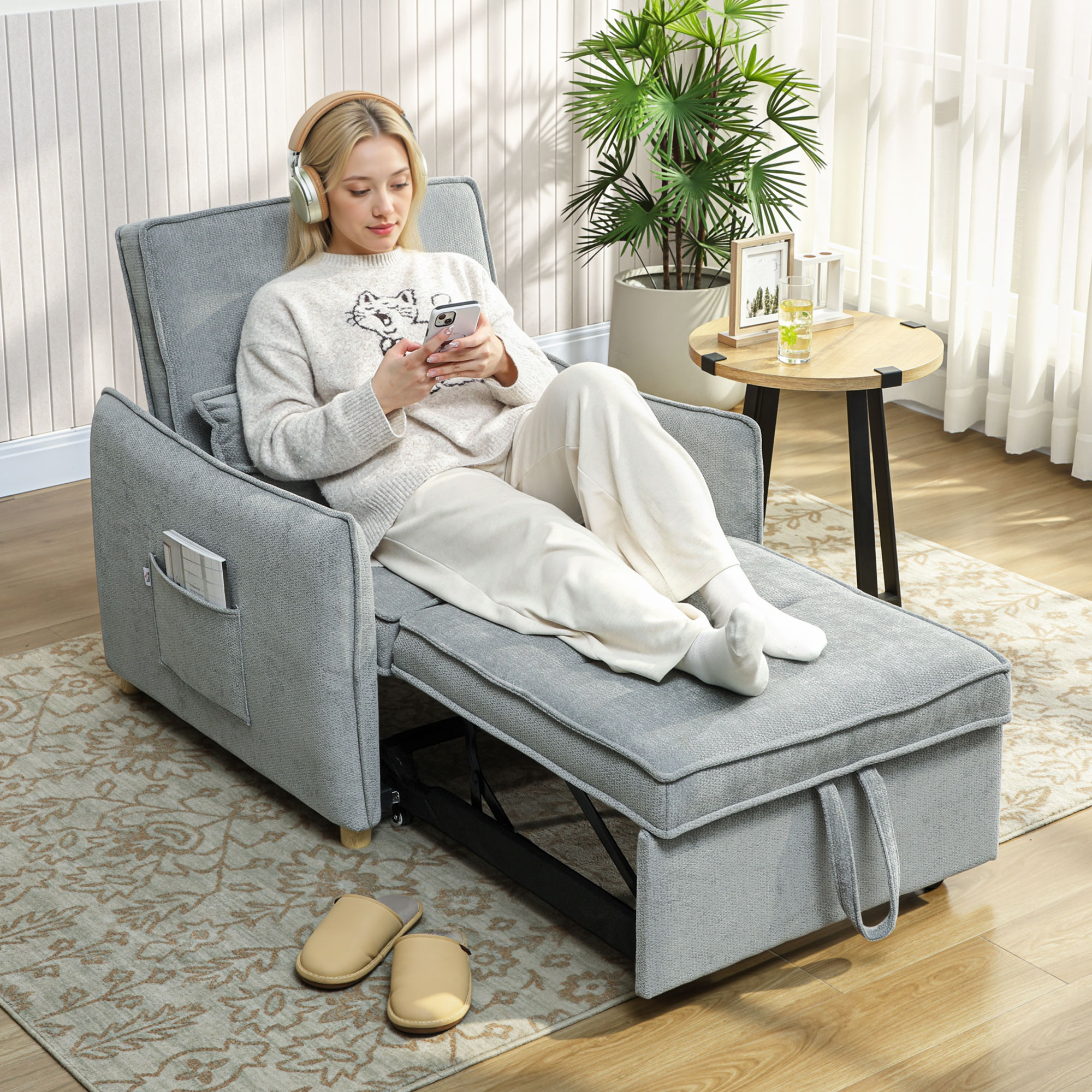Donna con cuffie e telefono su divano grigio, tavolino con pianta nelle vicinanze.
