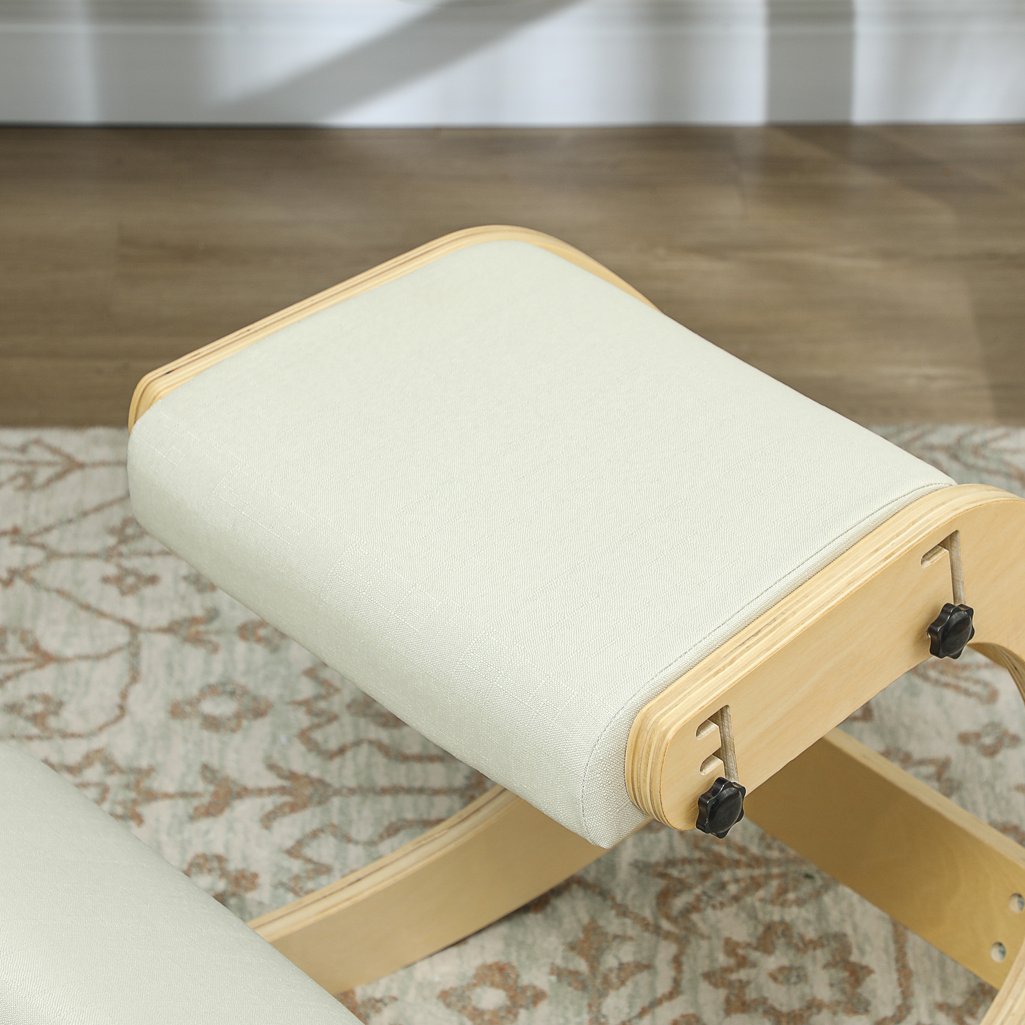 Una sedia inginocchiatoio beige con telaio in legno poggia su un tappeto fantasia.