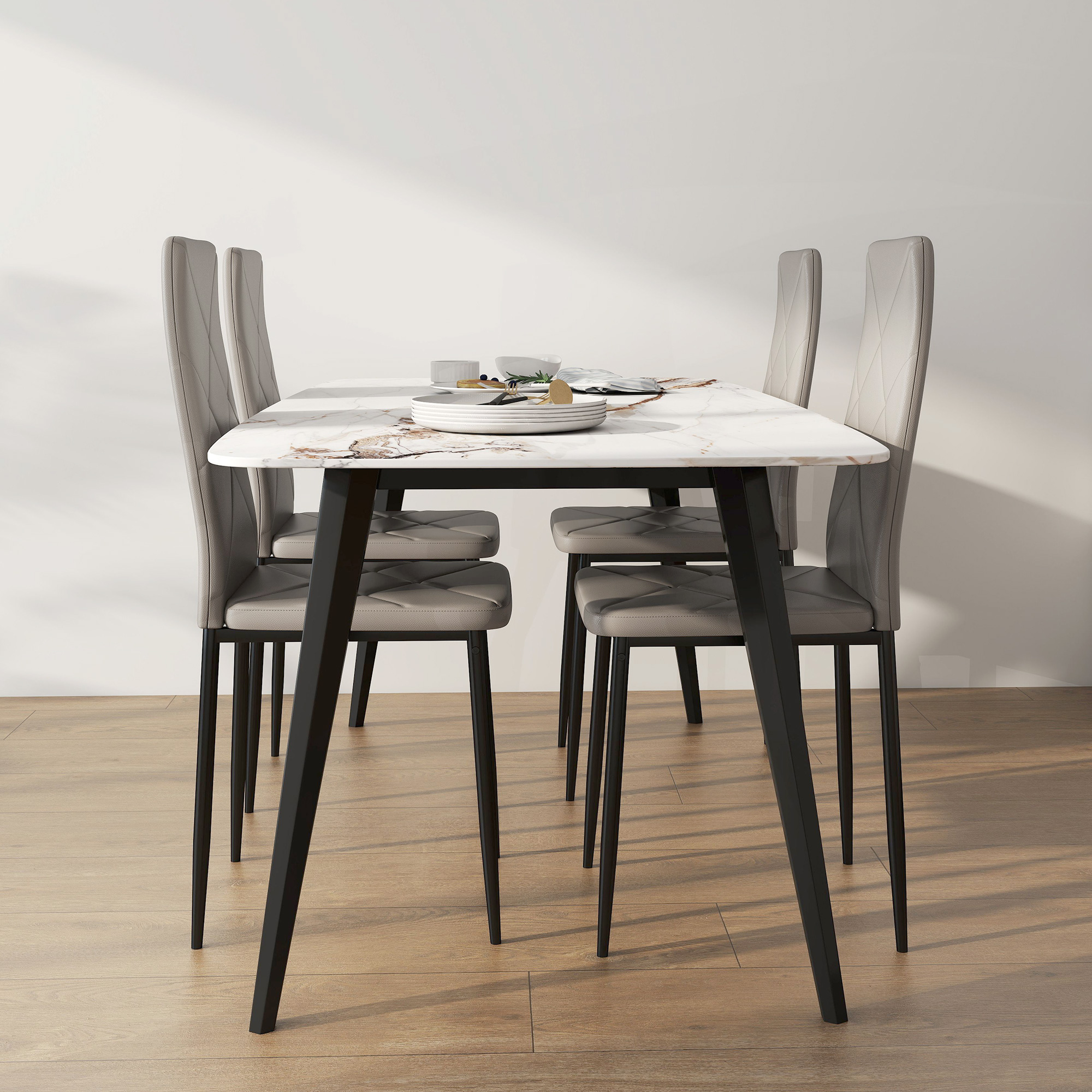 Un tavolo da pranzo con piano in marmo e quattro sedie grigie con gambe nere.
