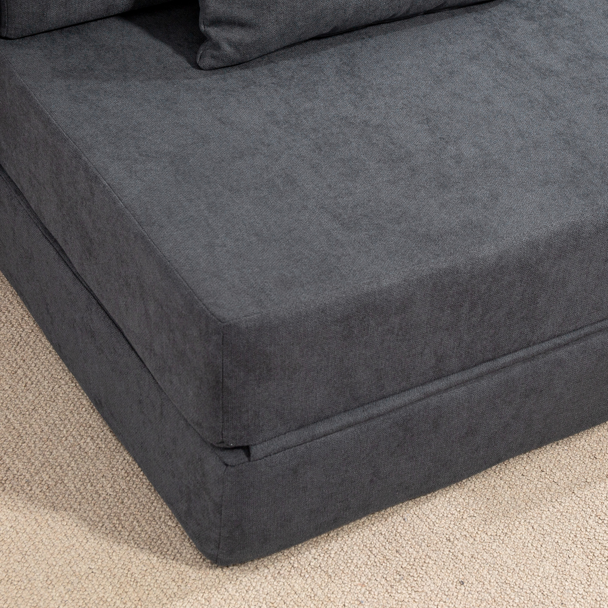 Una sezione di divano in tessuto grigio scuro su un tappeto beige.