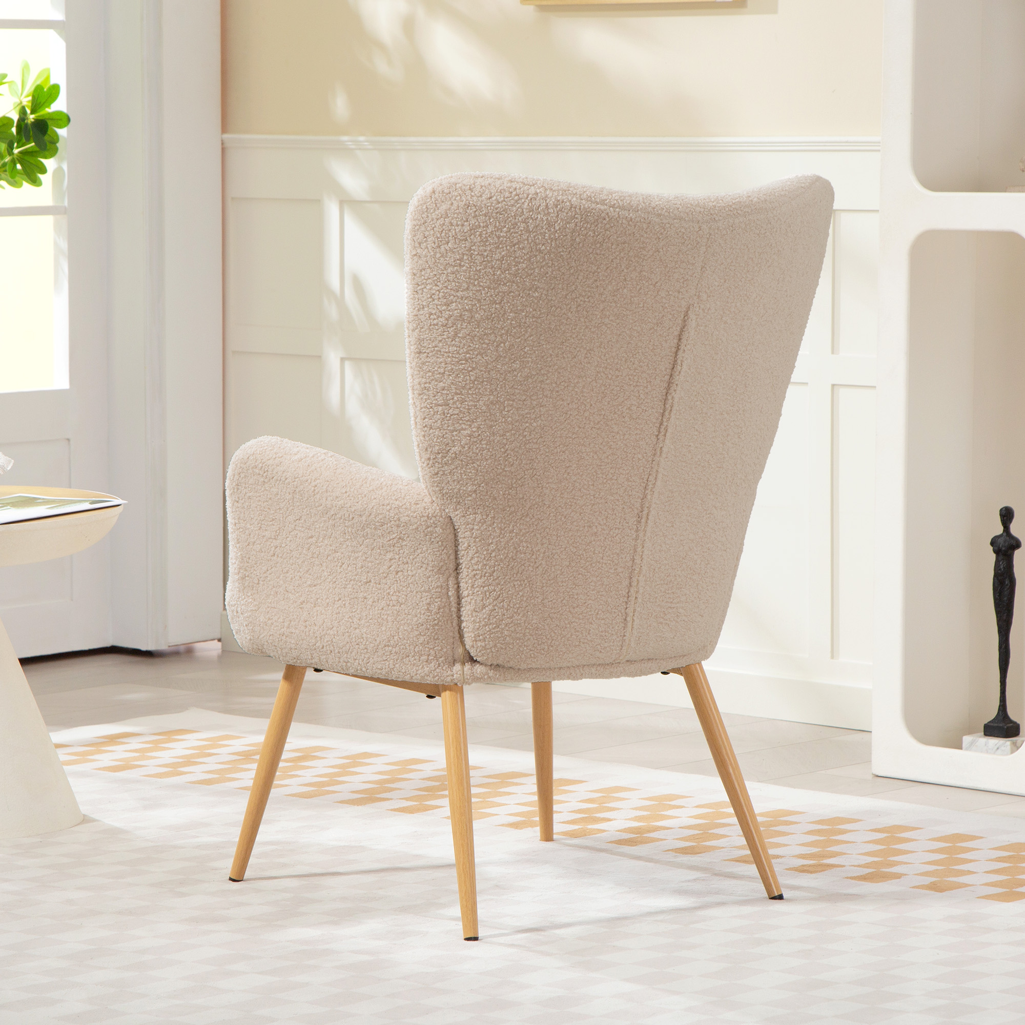 Una comoda poltrona in tessuto beige teddy con gambe in legno su un tappeto a scacchi.