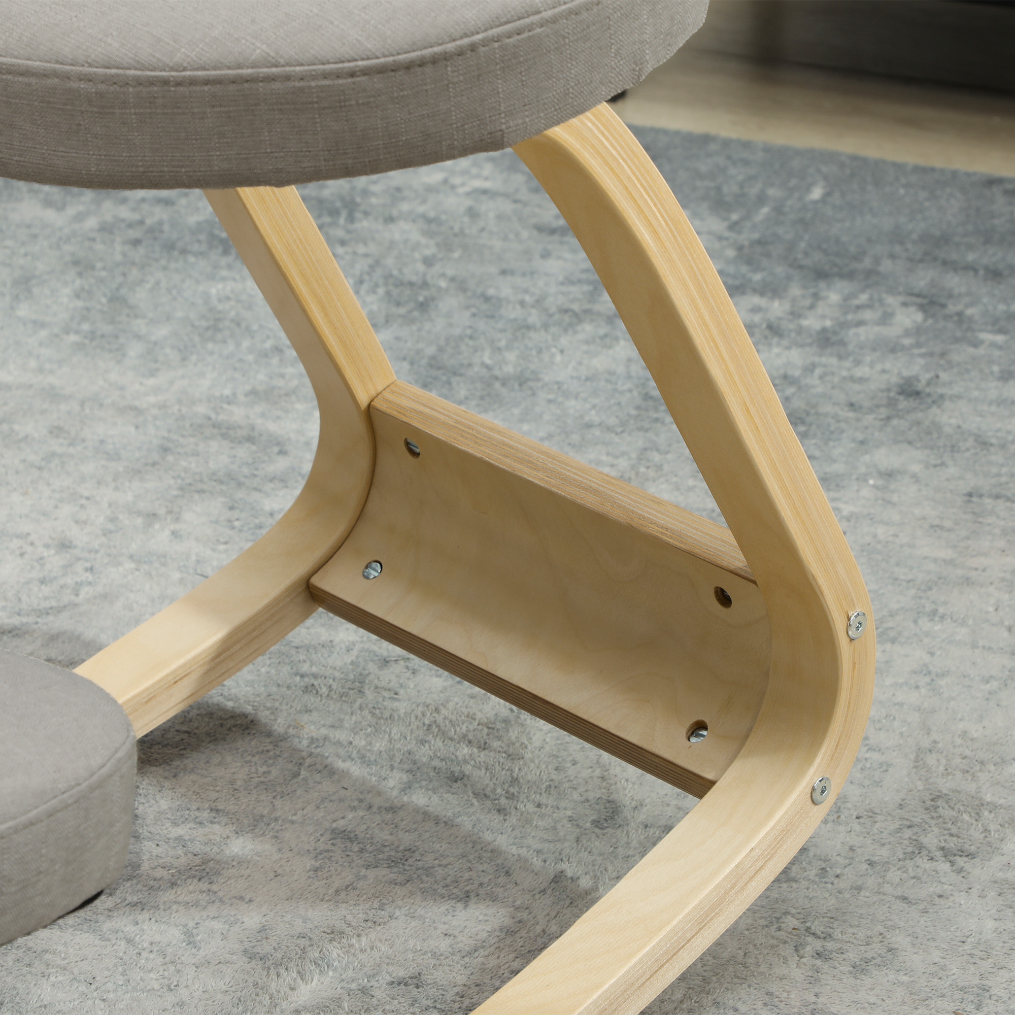 Una sedia inginocchiata grigia con telaio in legno e cuscini in tessuto su un tappeto grigio.