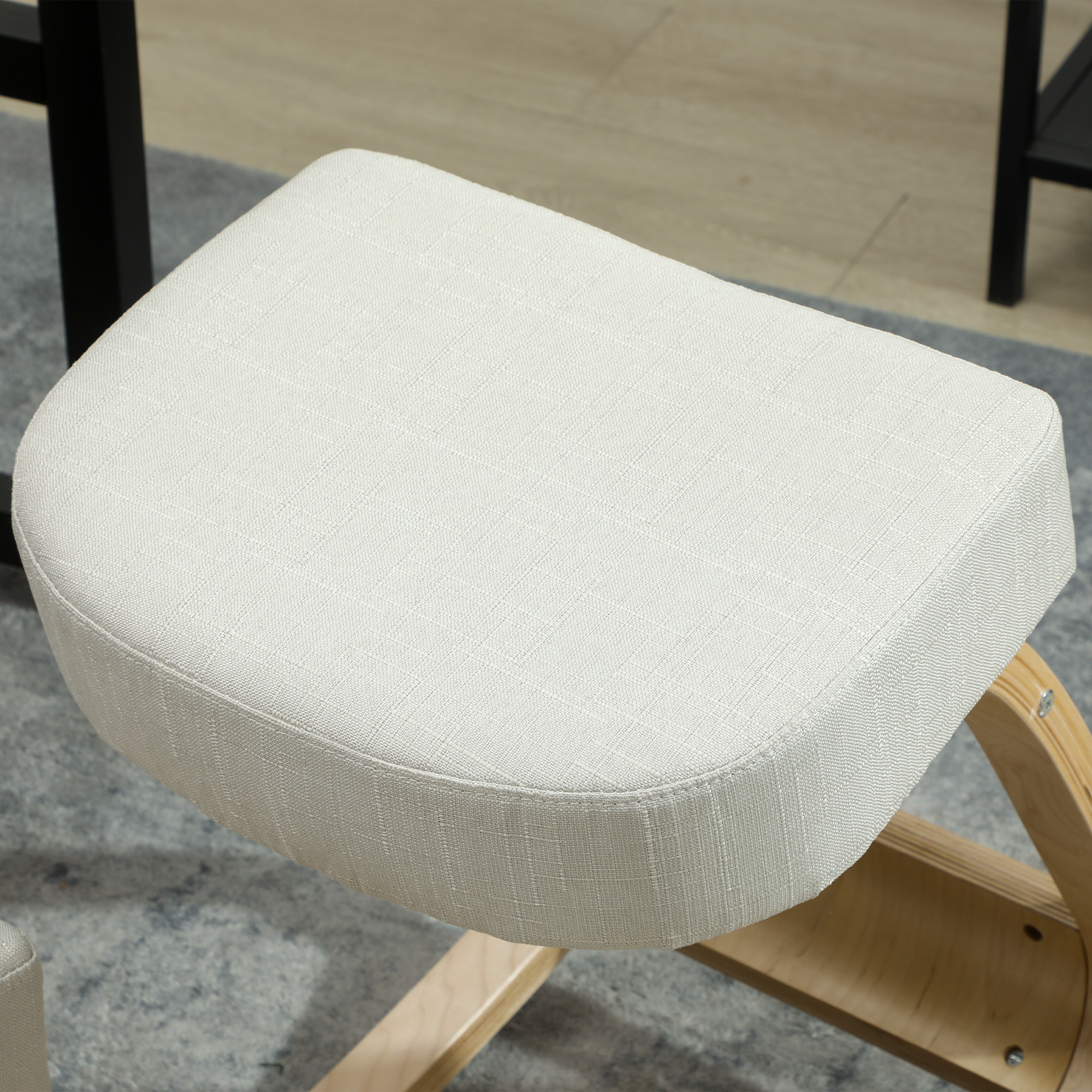 Una sedia inginocchiata bianca con telaio in legno su tappeto grigio.