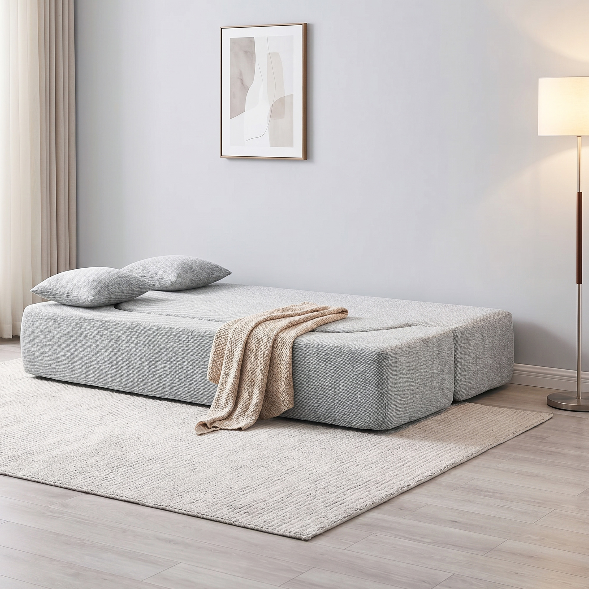 Un divano grigio con due cuscini e una coperta sopra, su un tappeto.