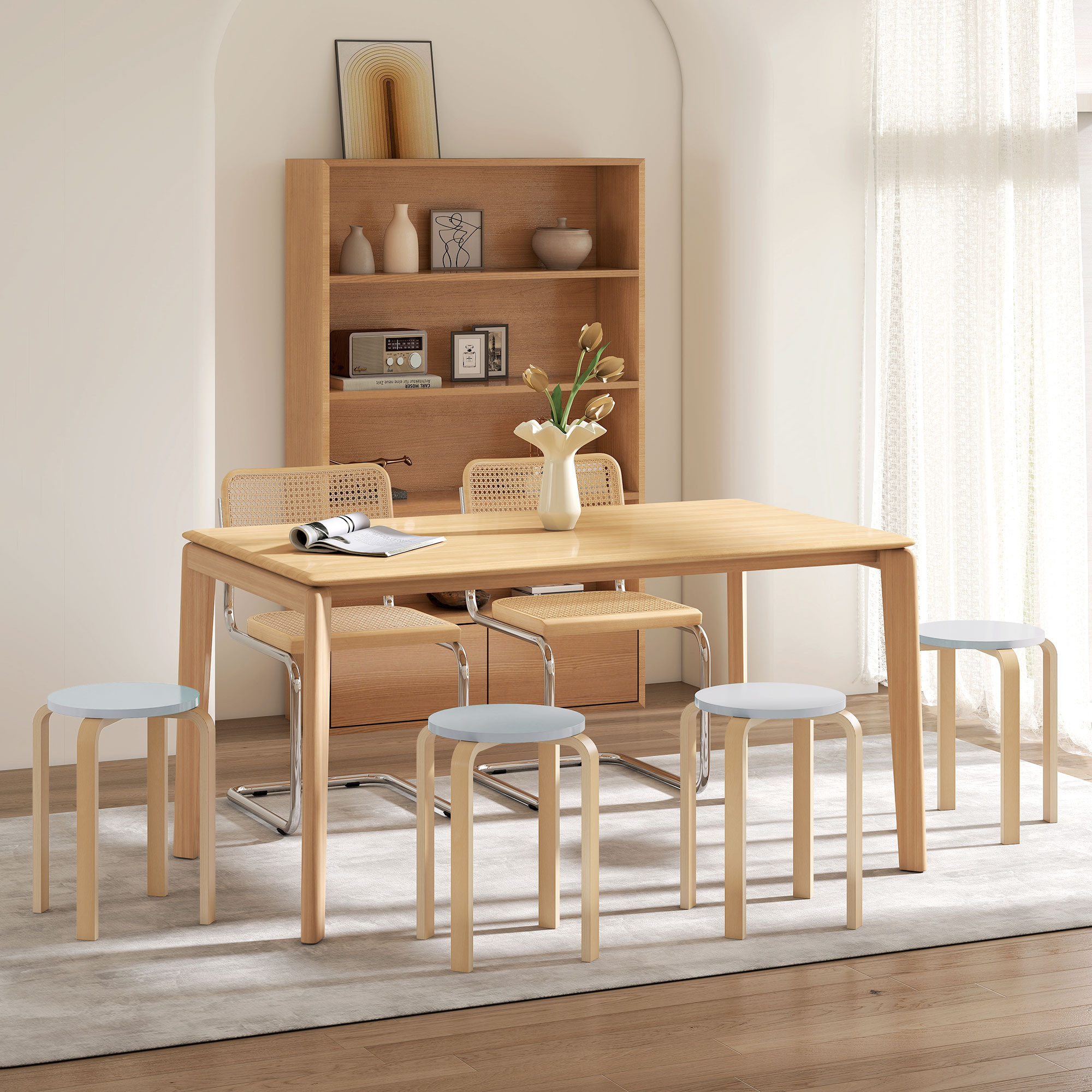 Tavolo in legno con sedie e sgabelli in una stanza luminosa con libreria.