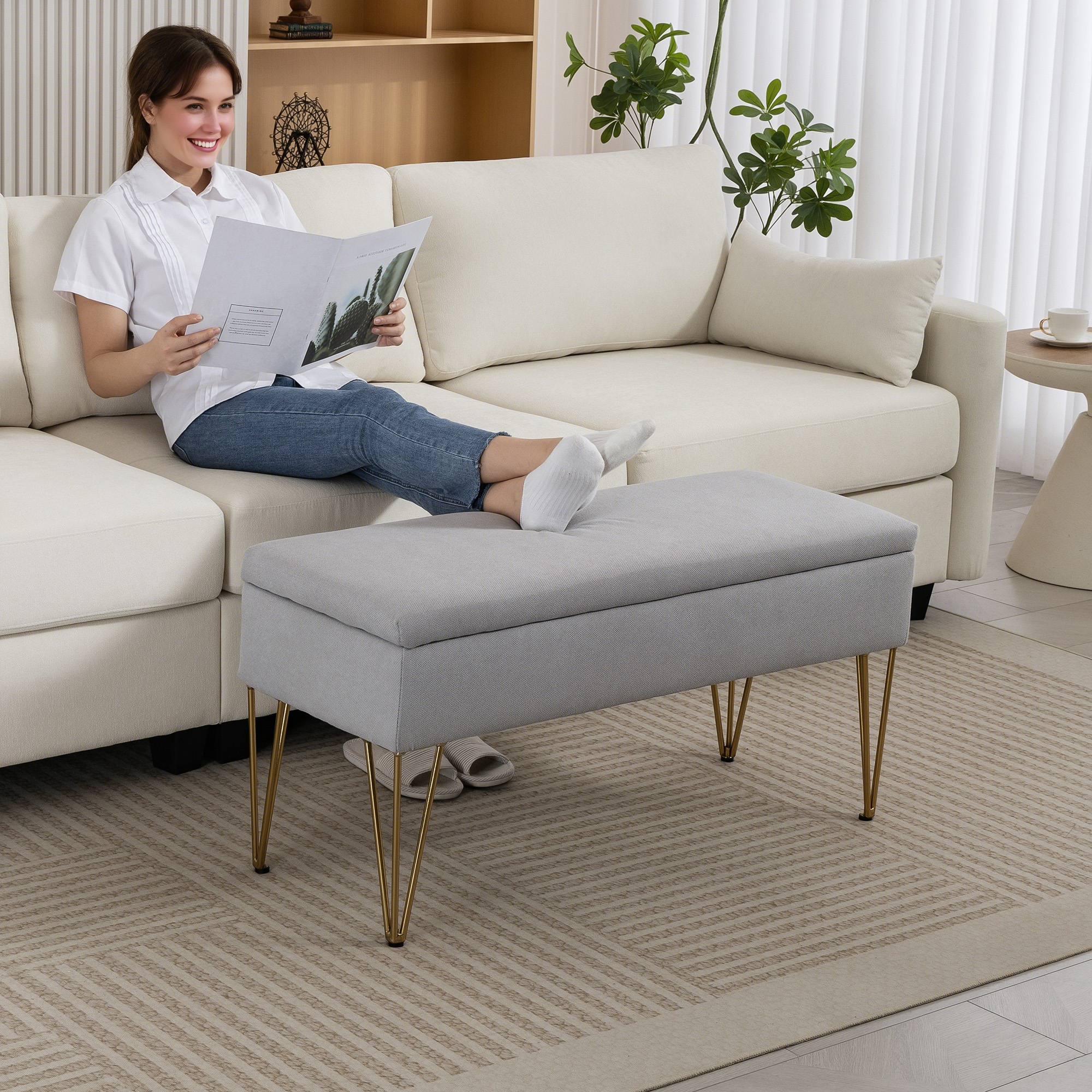 Una donna legge su un divano, un pouf è davanti.
