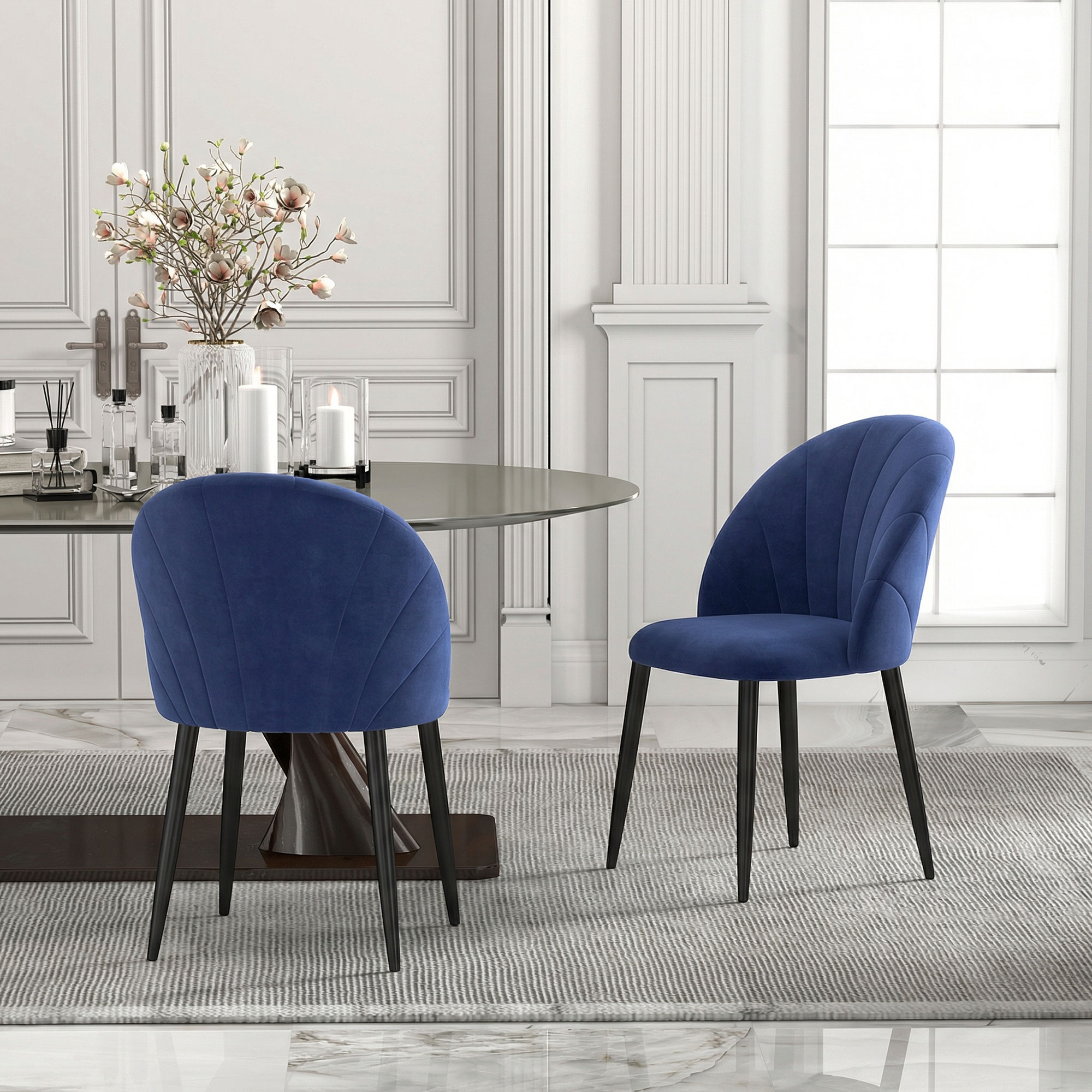 Due sedie blu in velluto su un tappeto davanti a un tavolo da pranzo.
