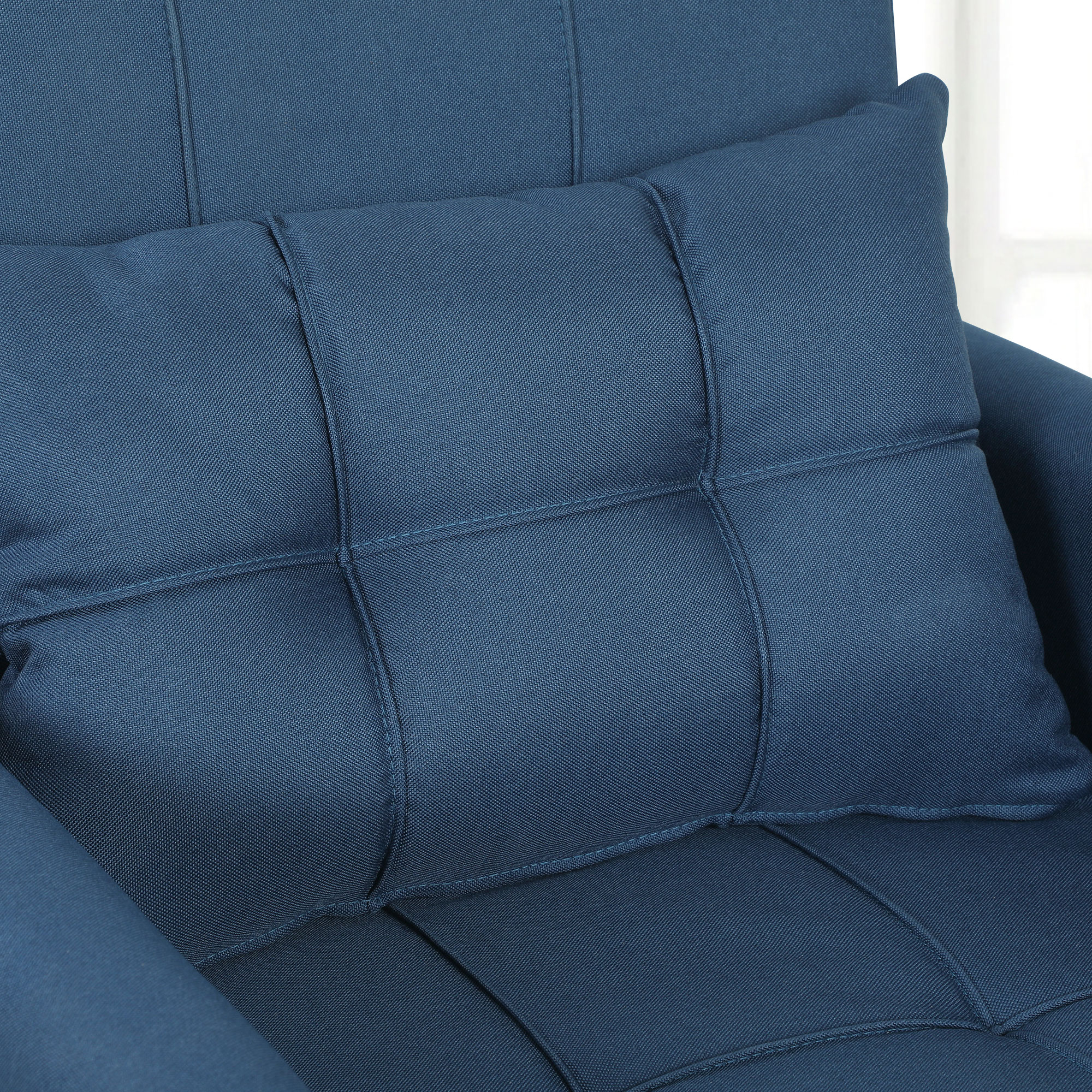 Una poltrona blu con cuscino trapuntato e cuciture.