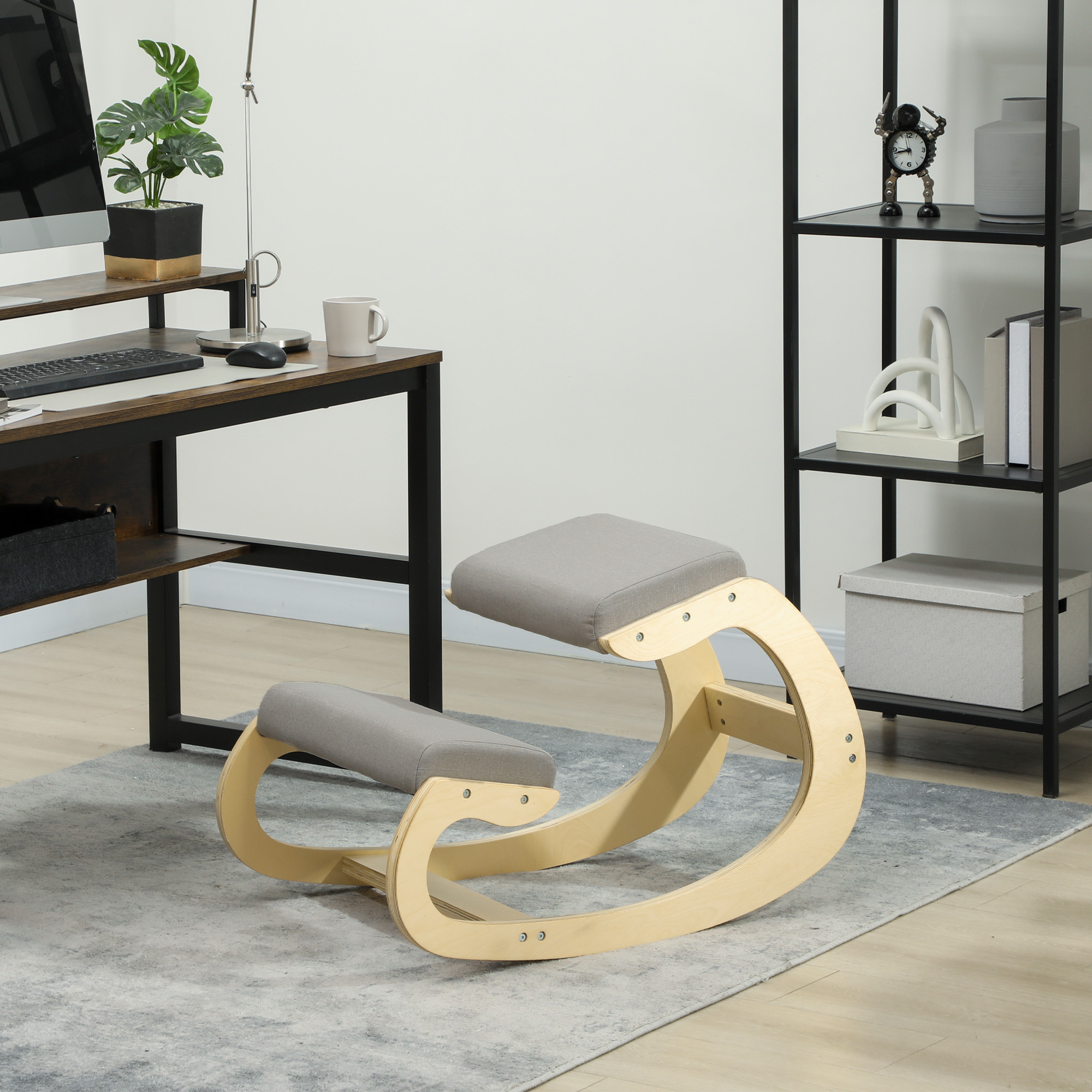 Una sedia inginocchiata in legno con cuscini grigi si trova su un tappeto.