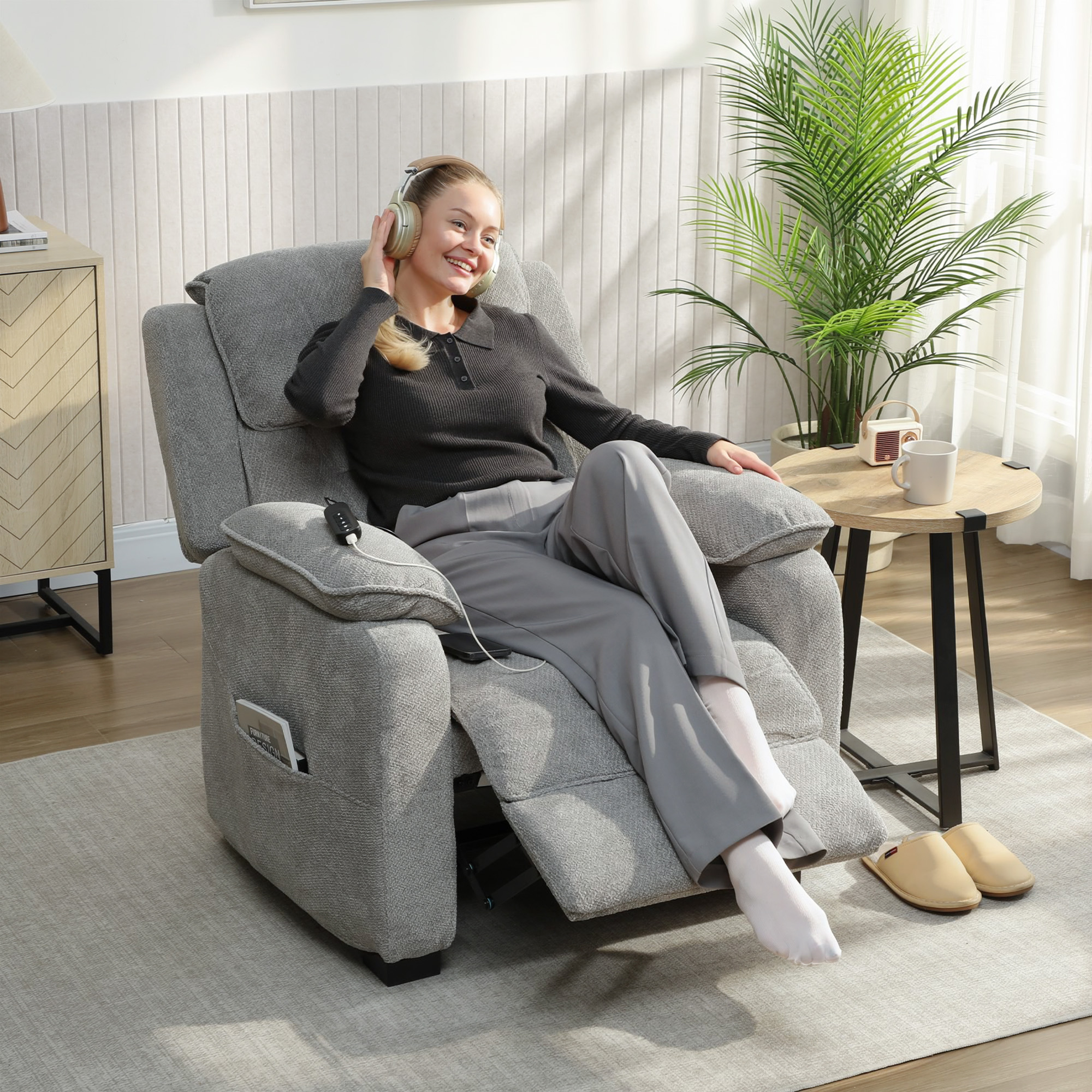 Una donna con cuffie si rilassa su una poltrona, con tavolino, pianta e mobile.