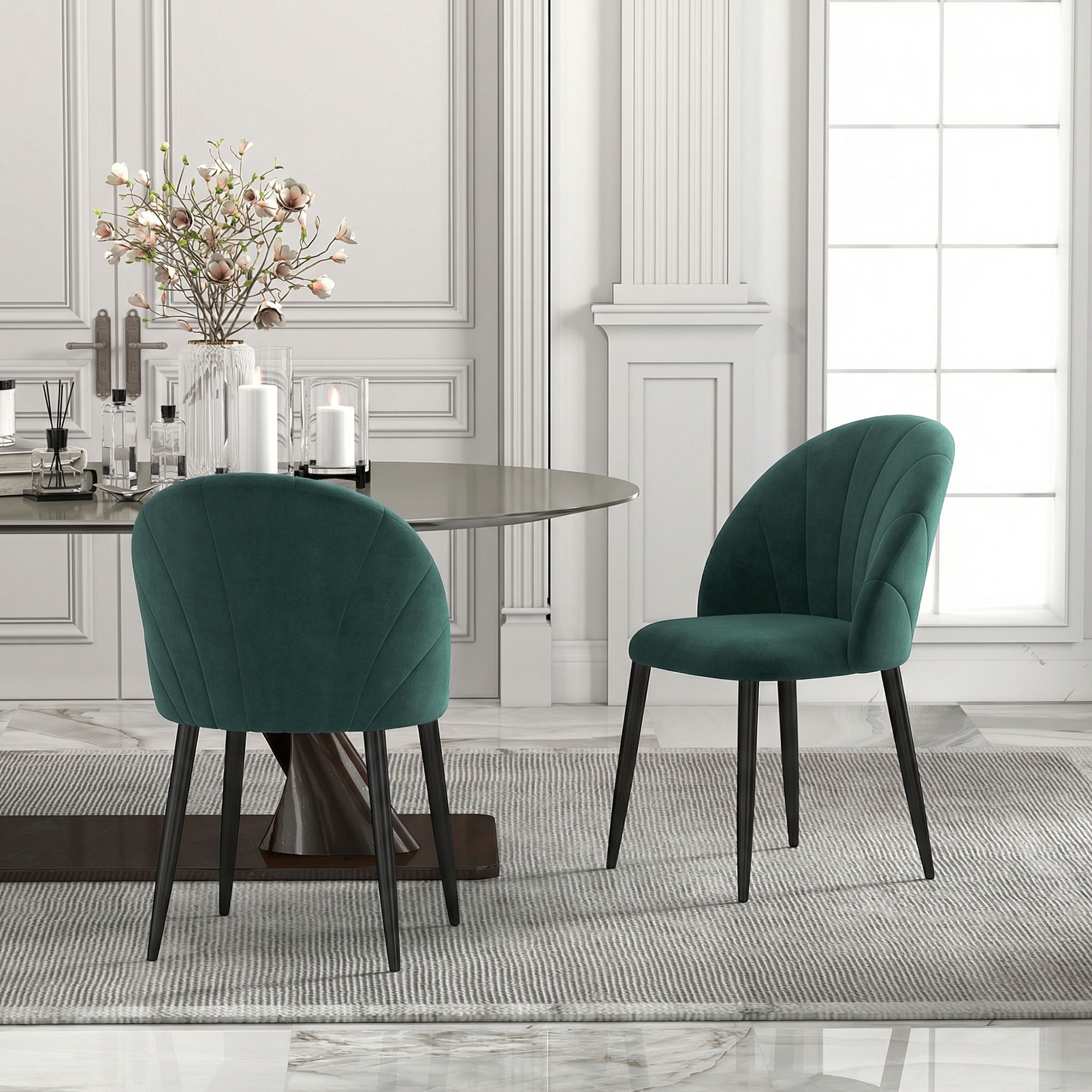 Due sedie in velluto verde davanti a un tavolo da pranzo in un'elegante sala da pranzo.