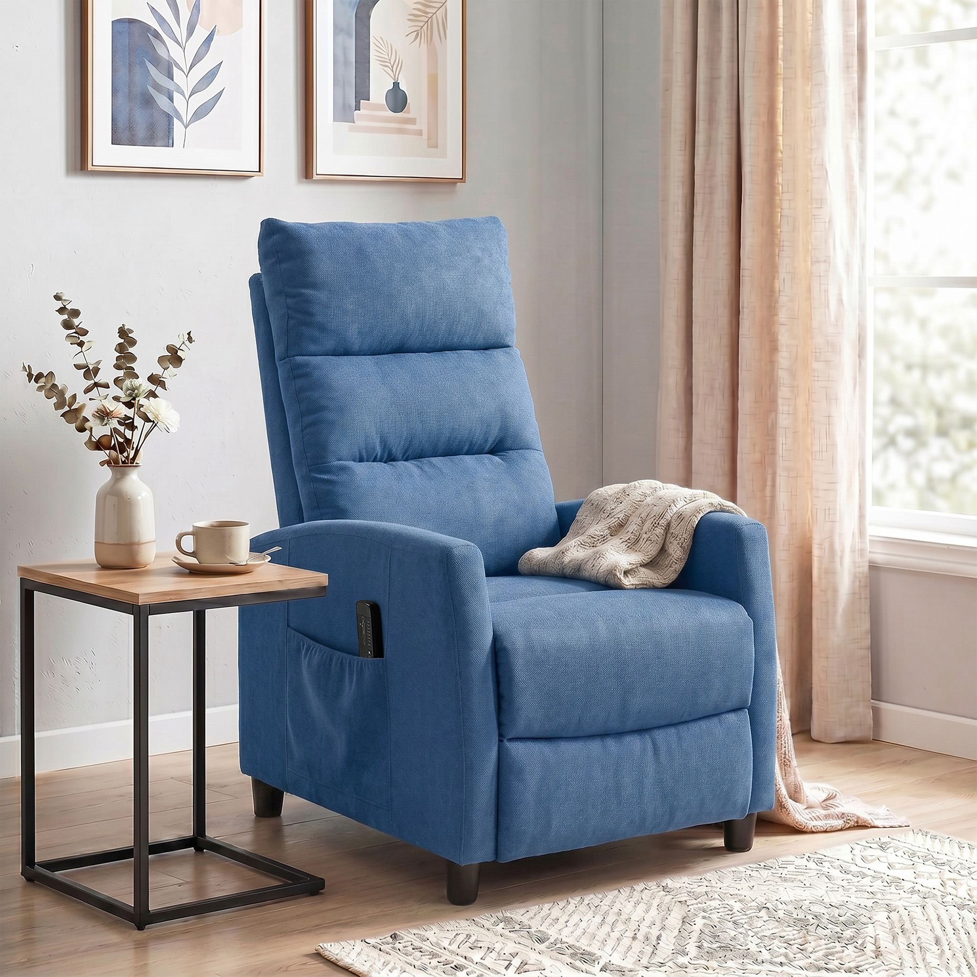Una poltrona reclinabile imbottita blu con coperta, accanto a un tavolino con vaso e tazza.