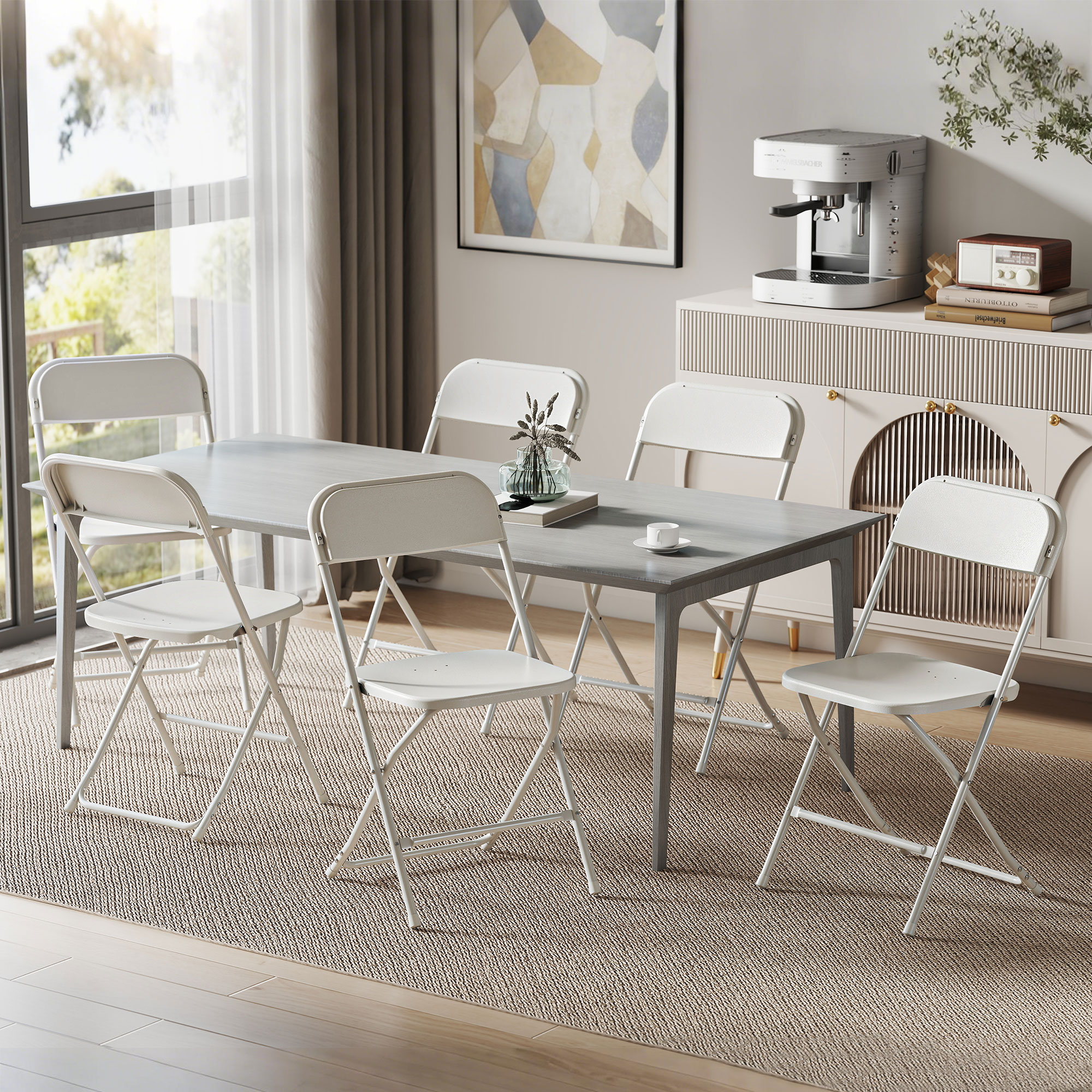 Una sala da pranzo con tavolo grigio, sedie pieghevoli bianche e credenza.