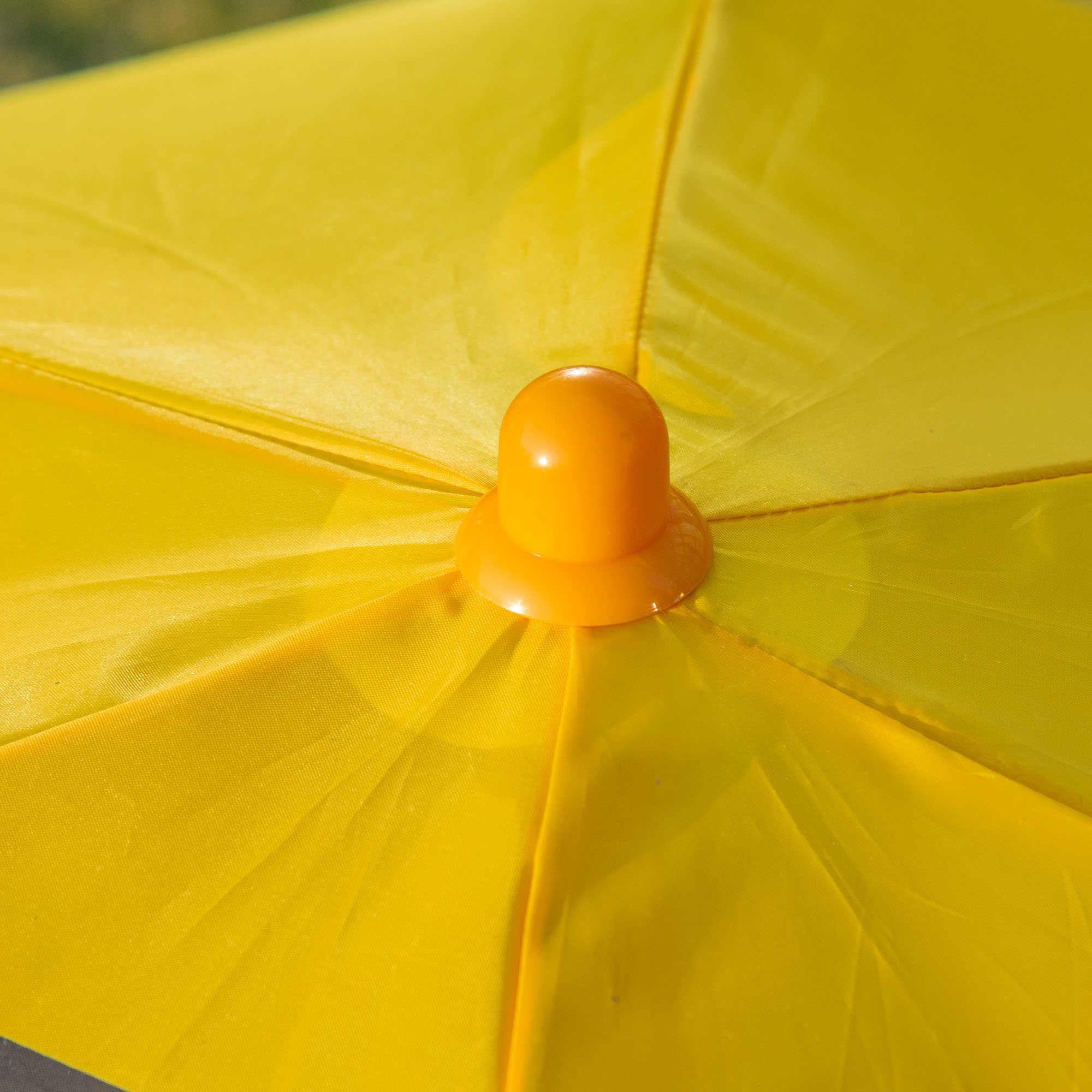 Un ombrello giallo con punta arancione su sfondo verde.