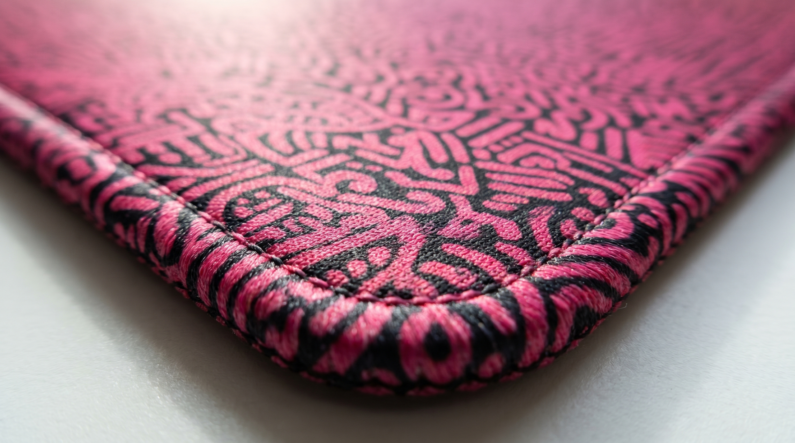 Dikişli kenarlı pembe ve siyah desenli mousepad yakın çekimi.