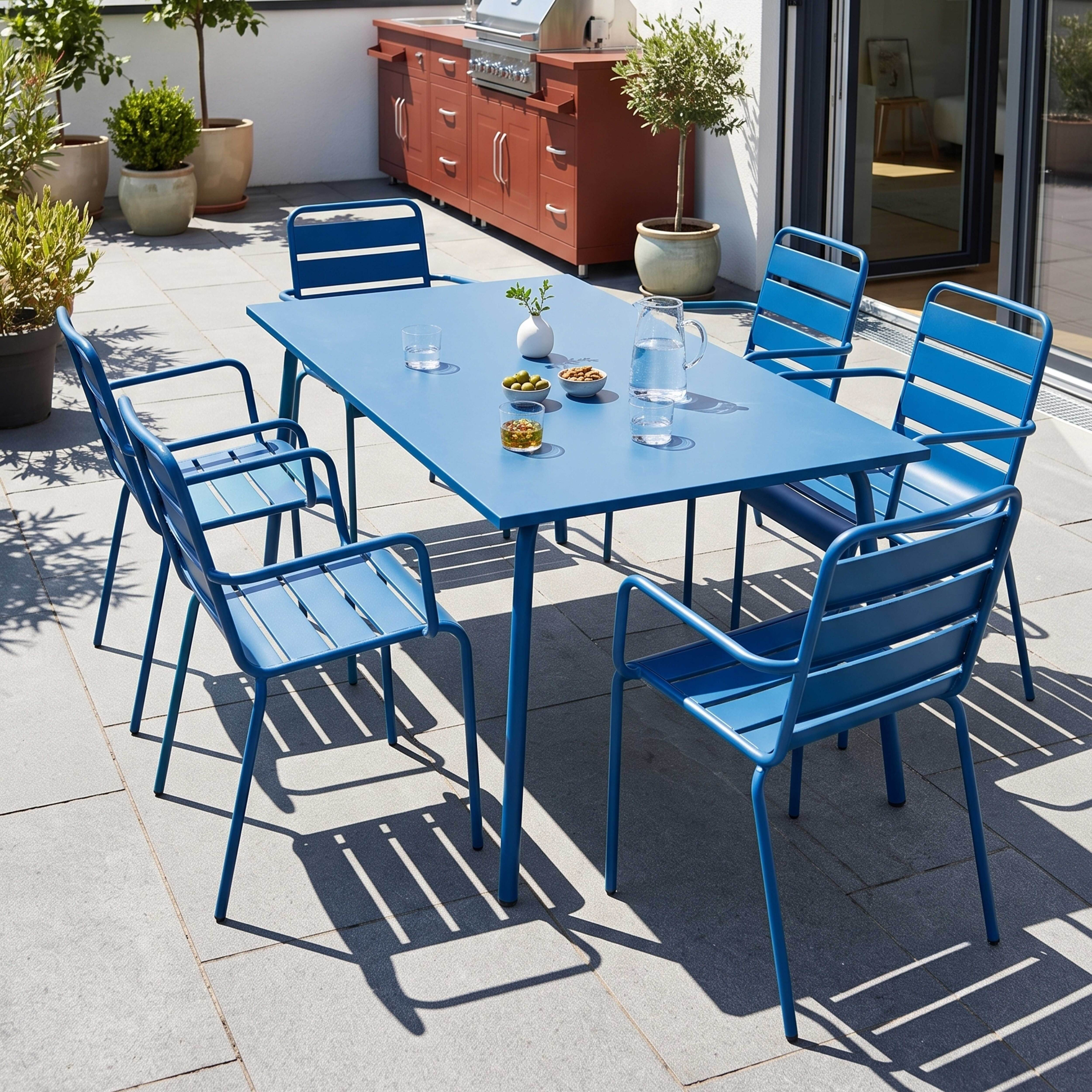 Blauer Gartentisch mit Stühlen, Grill und Pflanzen im Freien.