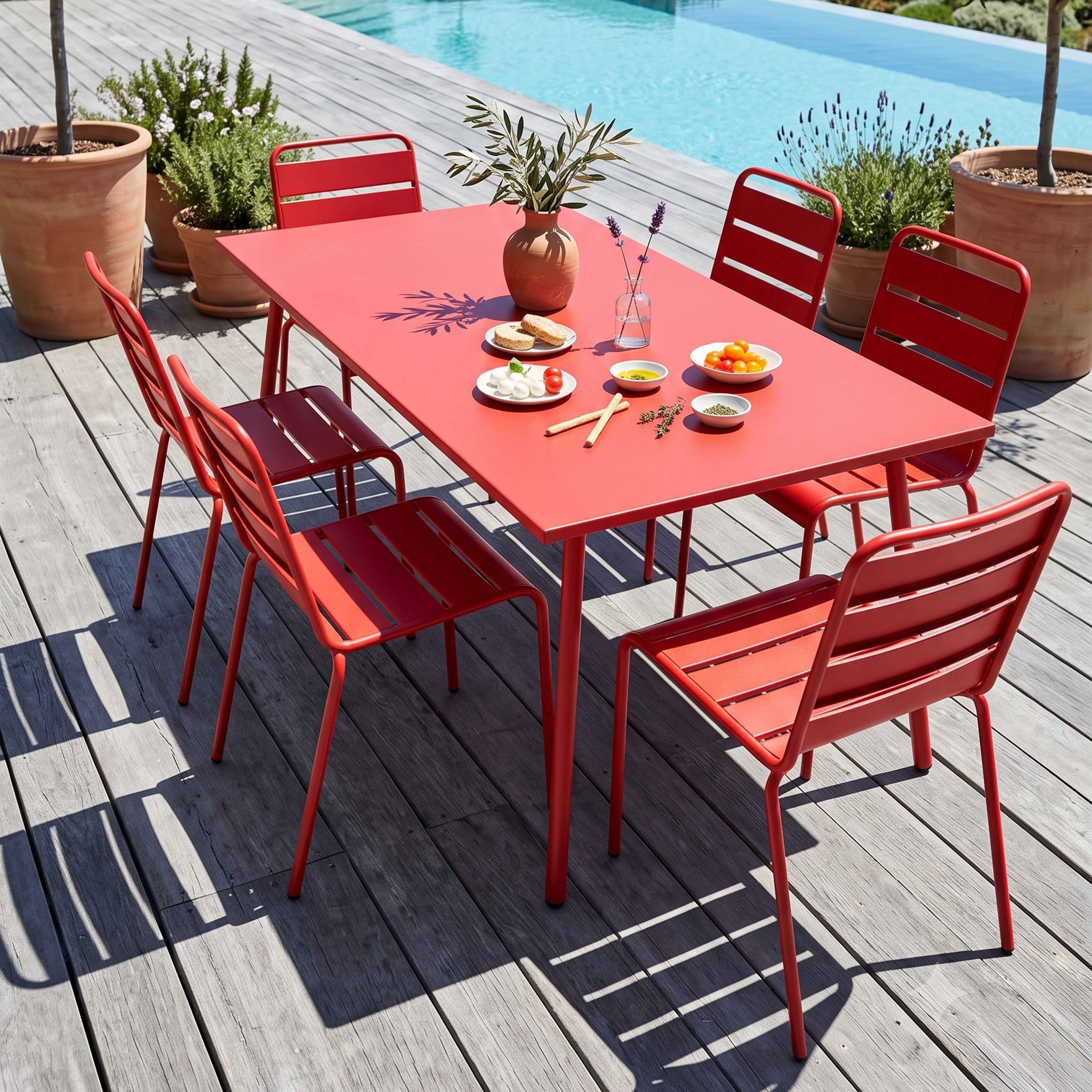 Ein roter Tisch und Stühle stehen auf einer Holzterrasse am Pool mit Essen.