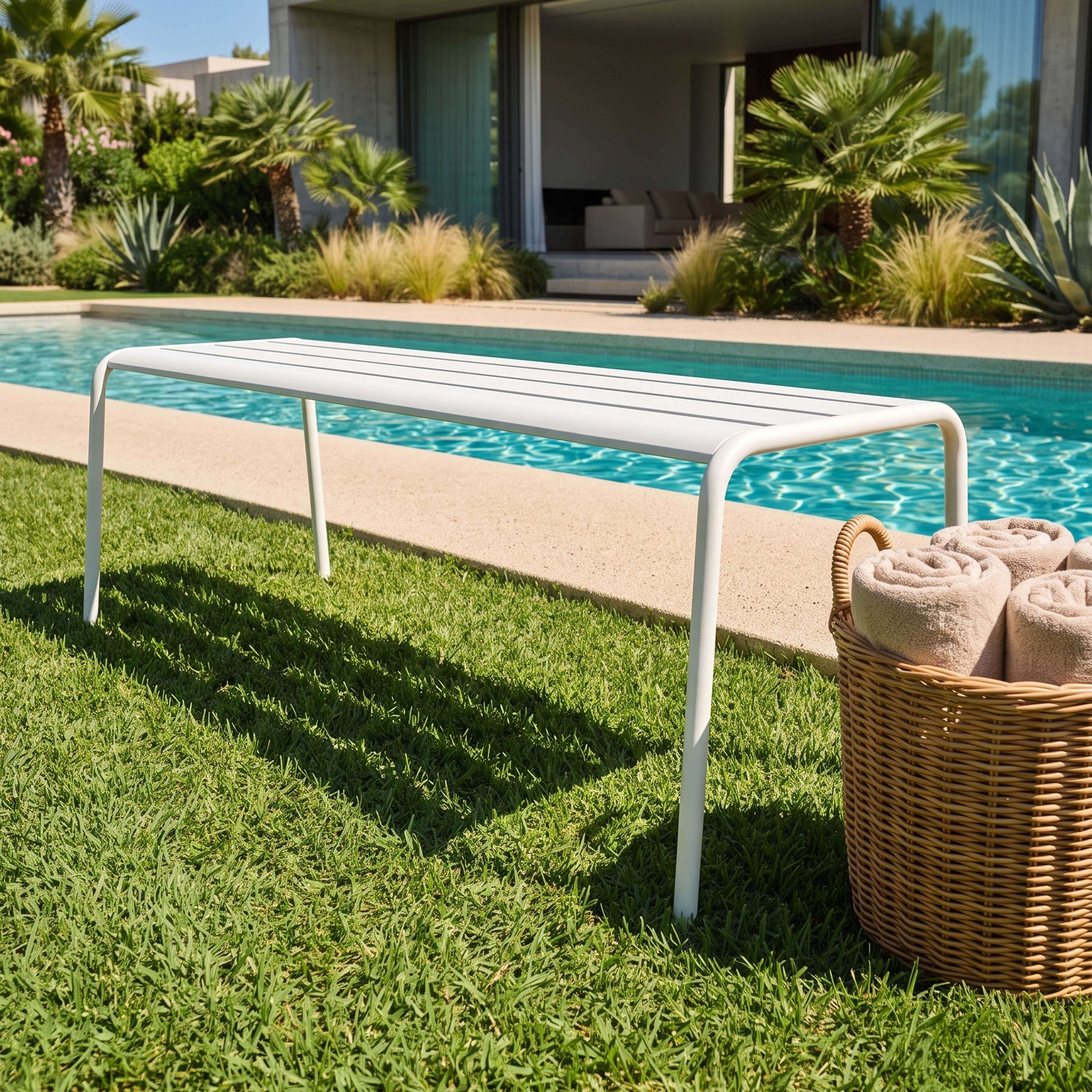 Weiße Liege am Pool mit Handtüchern im Korb.