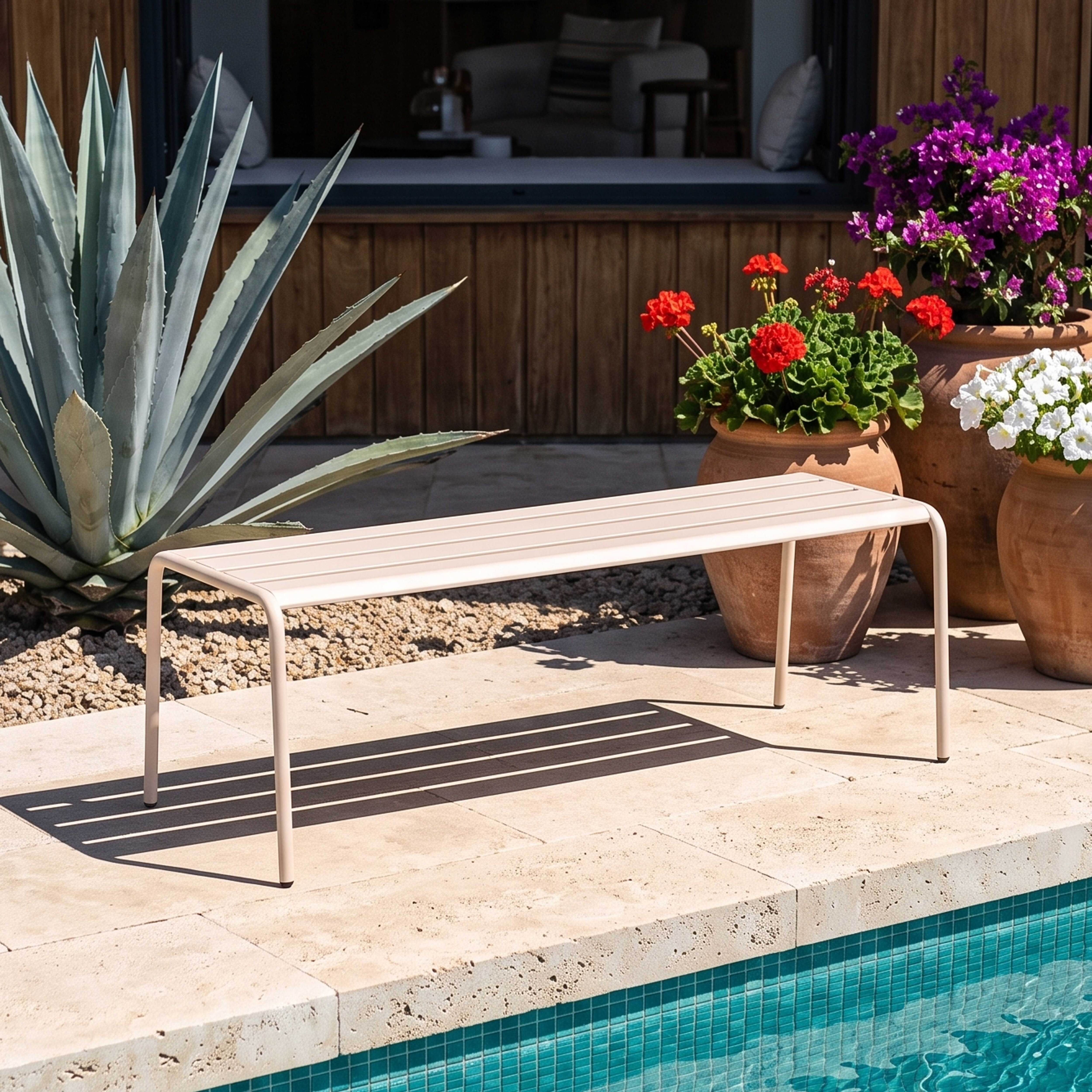 Eine beigefarbene Lamellenbank steht auf einer gefliesten Terrasse neben einem Pool.