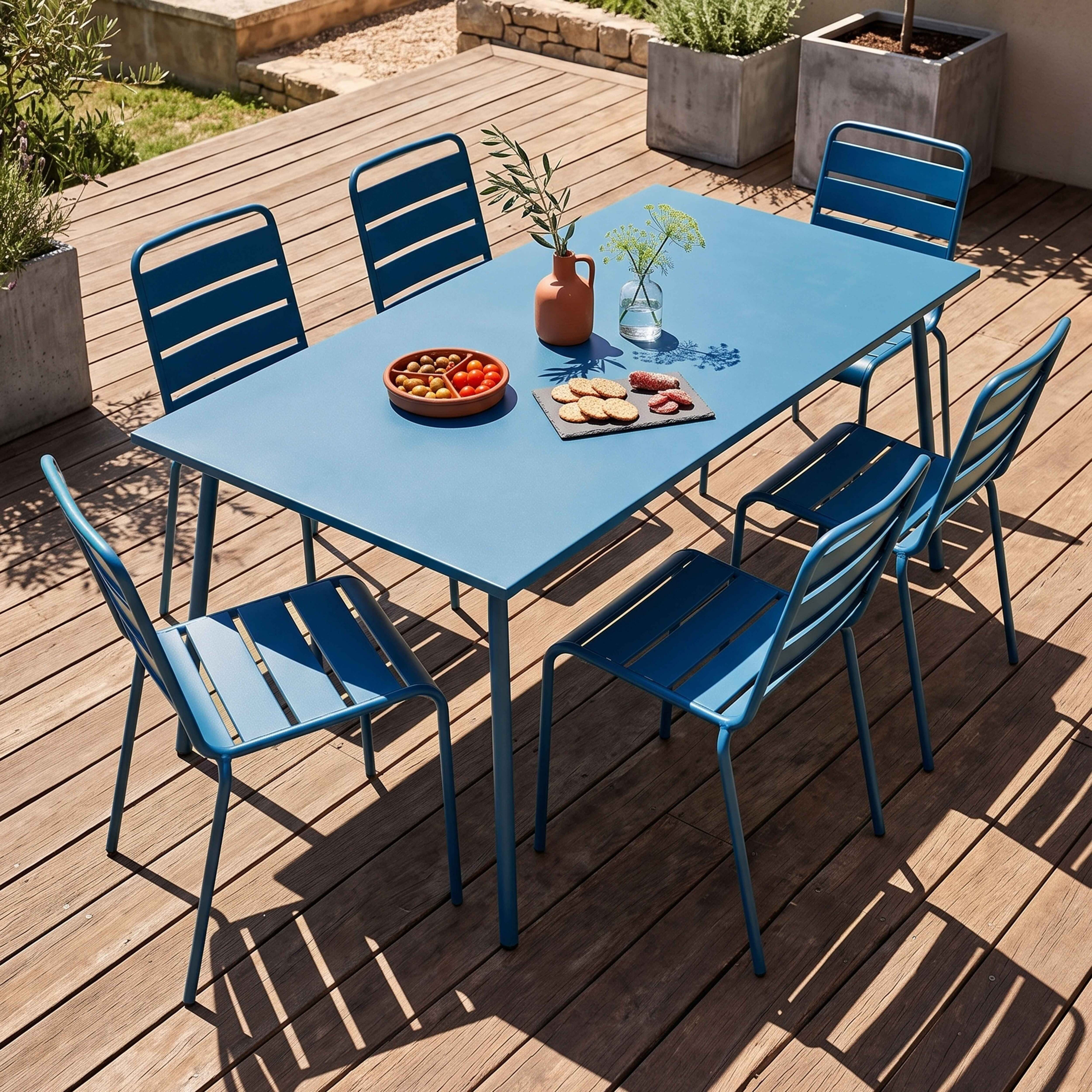 Ein blauer Gartentisch mit Stühlen auf einer Holzterrasse, dekoriert mit Snacks.