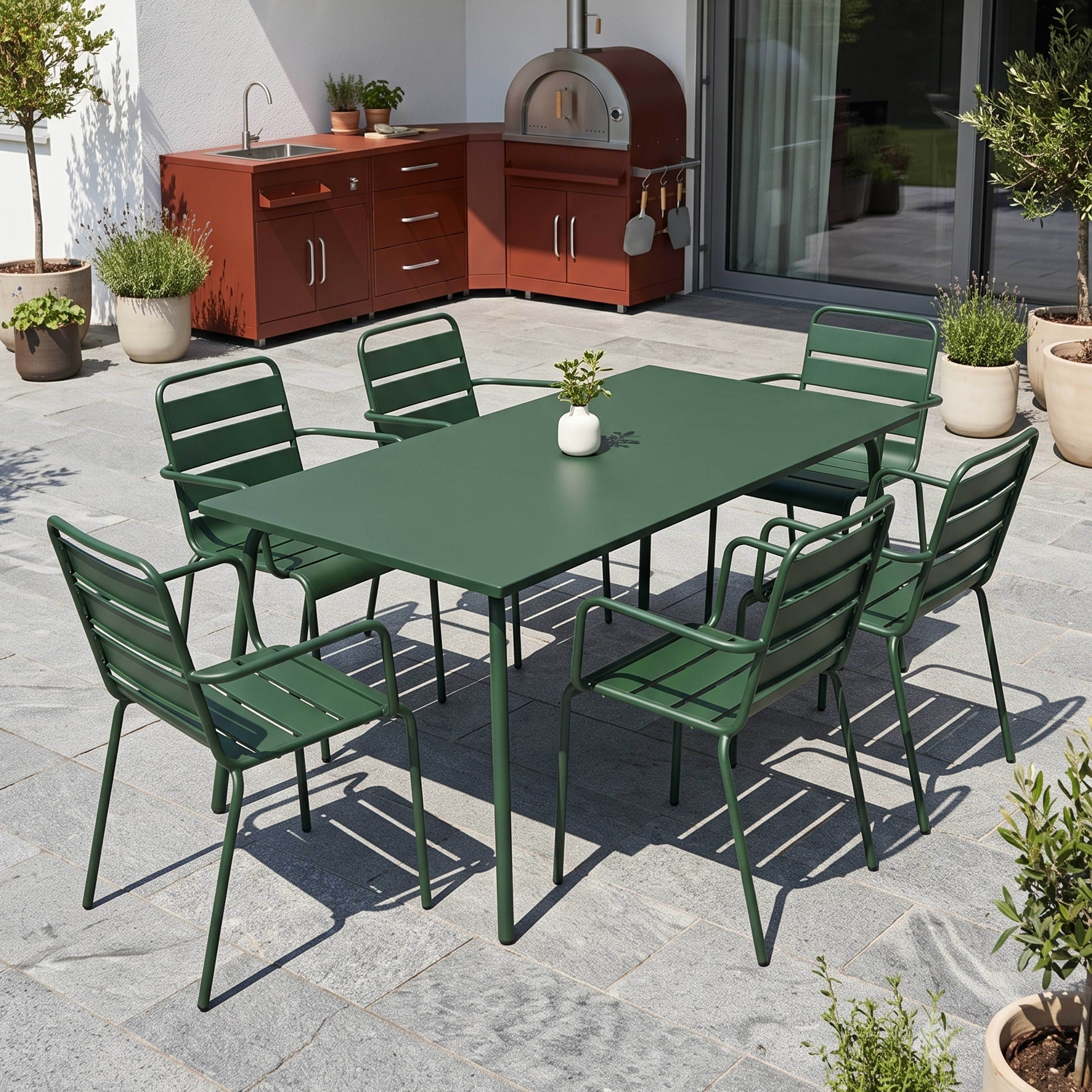 Dunkelgrüner Gartentisch mit sechs Stühlen auf gepflasterter Terrasse.