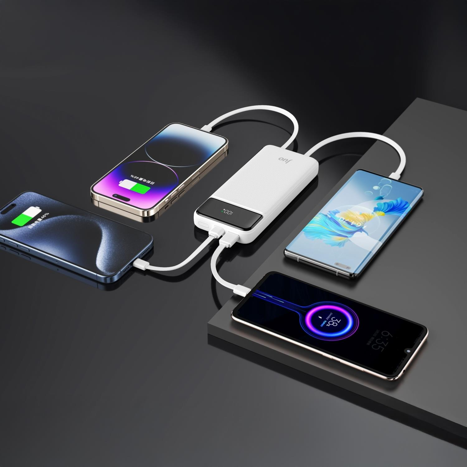 Beyaz bir powerbank, karanlık bir masada dört akıllı telefonu şarj ediyor.
