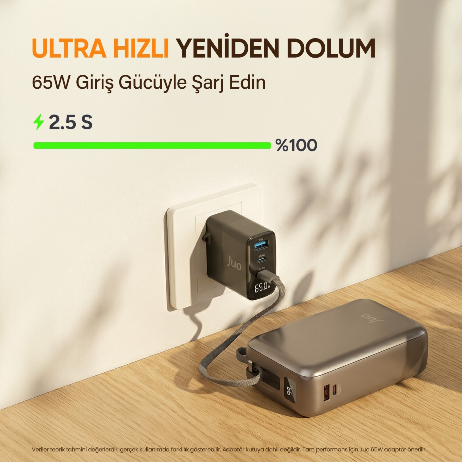 Gri bir powerbank, beyaz bir duvar prizine takılı siyah adaptörle şarj oluyor.