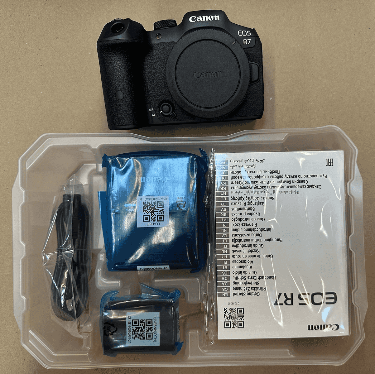 Cámara Canon EOS R7 con accesorios en embalaje plástico.