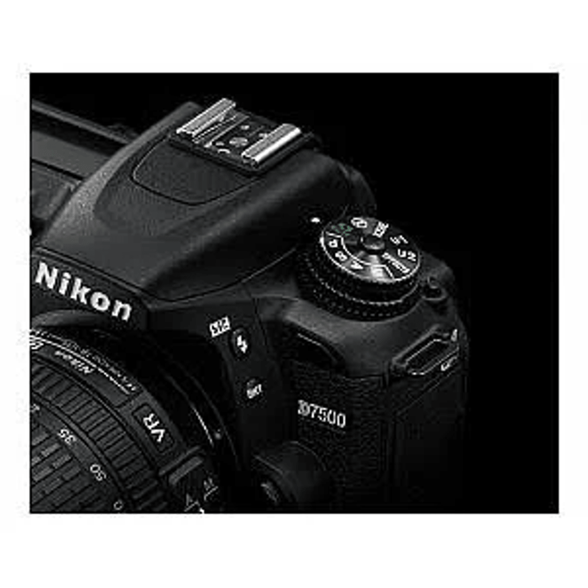 Primo piano di una fotocamera reflex Nikon D7500 nera, con focus sulla ghiera delle modalità e la slitta a contatto.