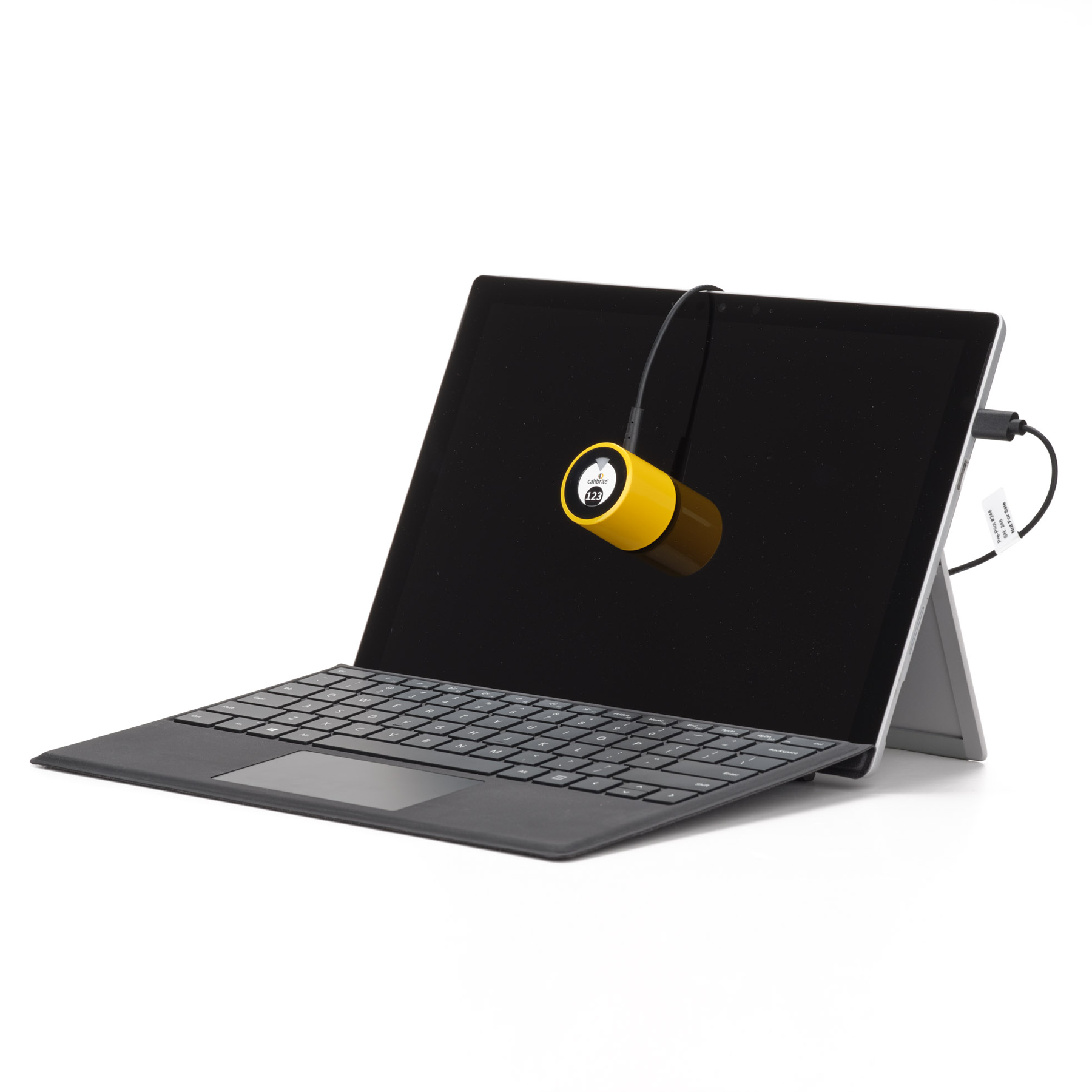 Ein gelbes Kalibriergerät ist an einem Laptop mit Tastatur befestigt.