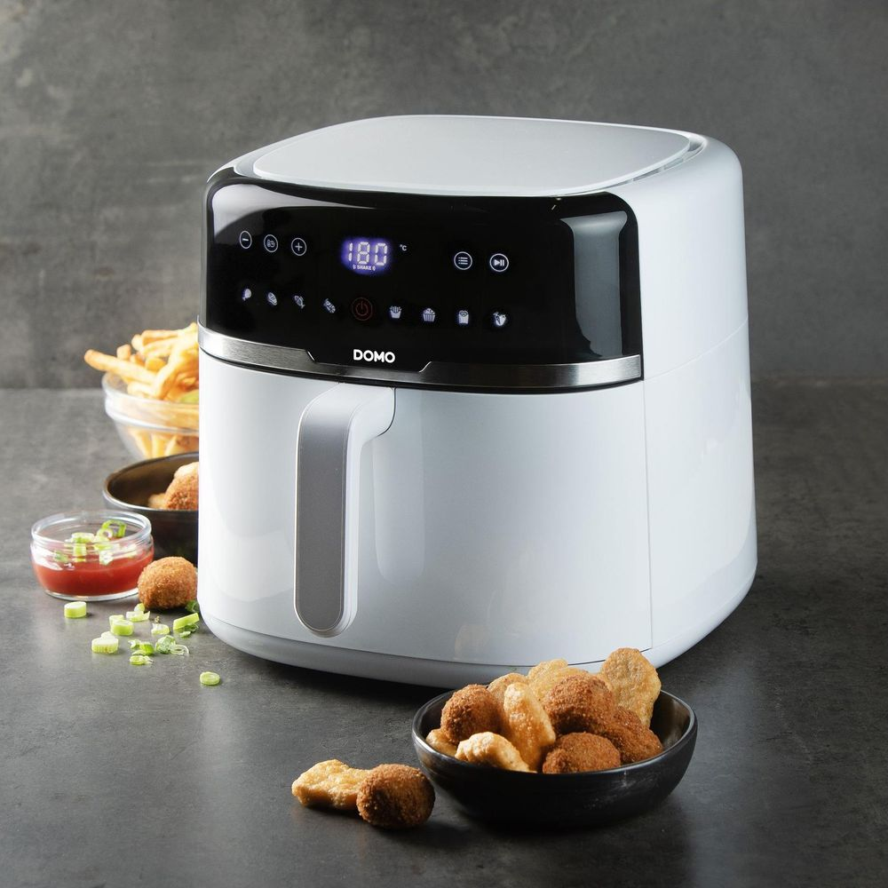 Weiße Heißluftfritteuse mit digitalen Anzeigen neben Pommes und Snacks.