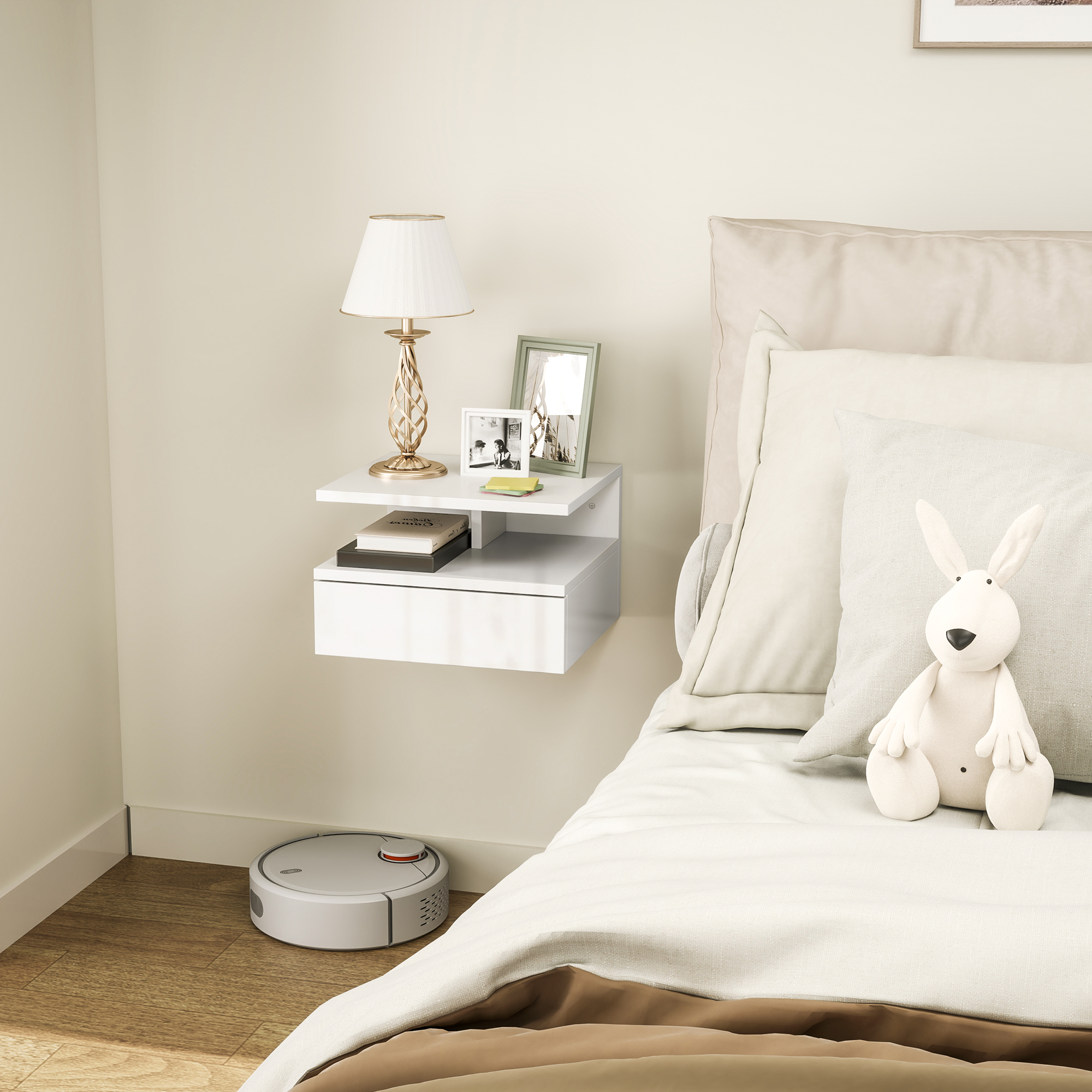Un comodino sospeso bianco con cassetto, lampada, cornici e libri.