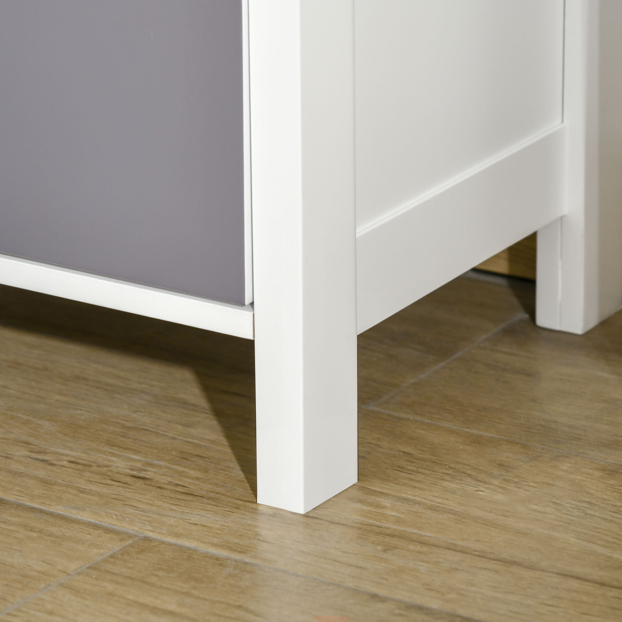 Gambe bianche di mobili su pavimento in legno. Lato grigio del mobile visibile.