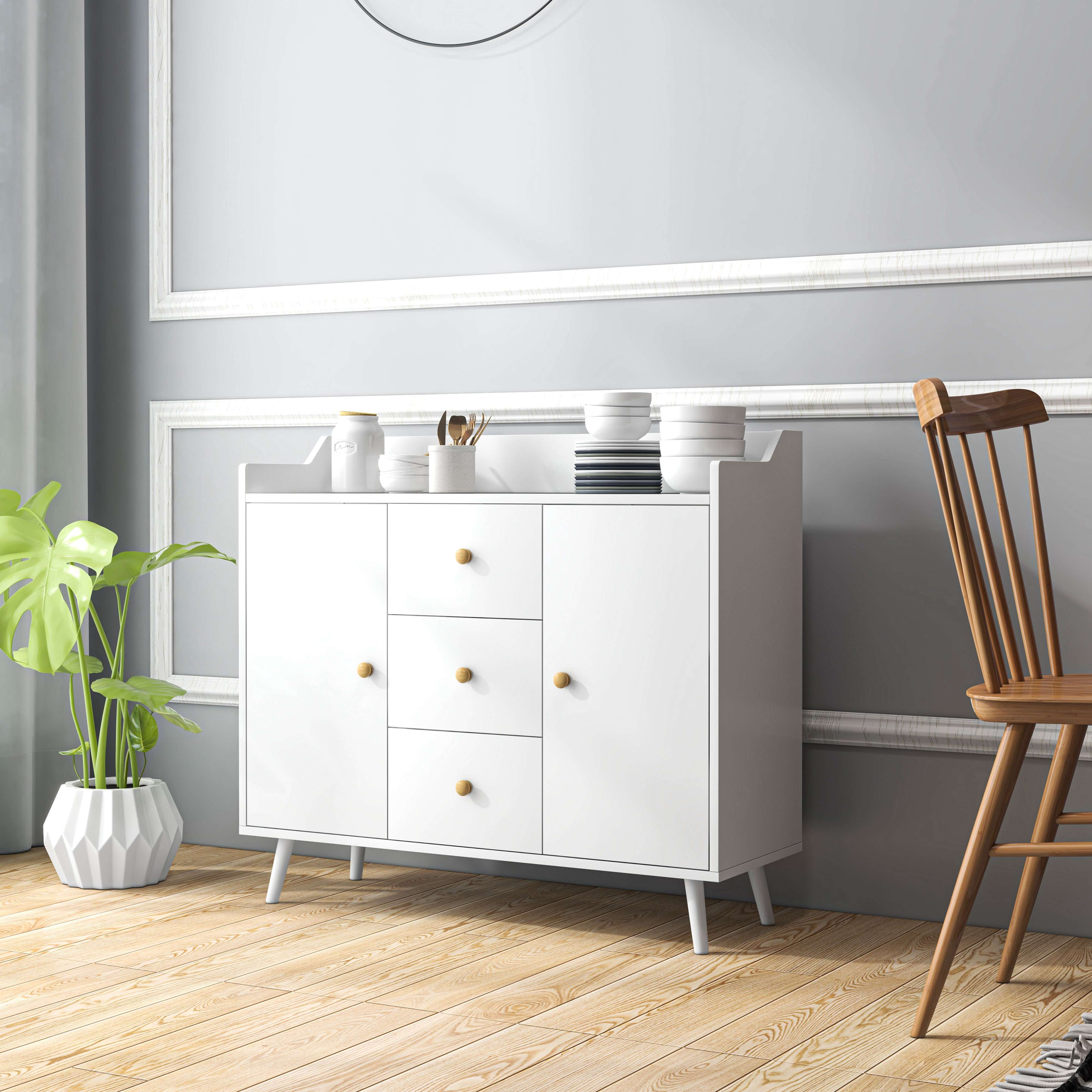 Una credenza bianca con pavimenti in legno, una pianta e una sedia.